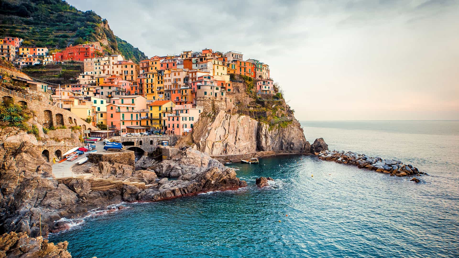A picturesque view of the colorful houses of Manarola, a village in Cinque Terre, Italy, perched on a cliff overlooking the Ligurian Sea.