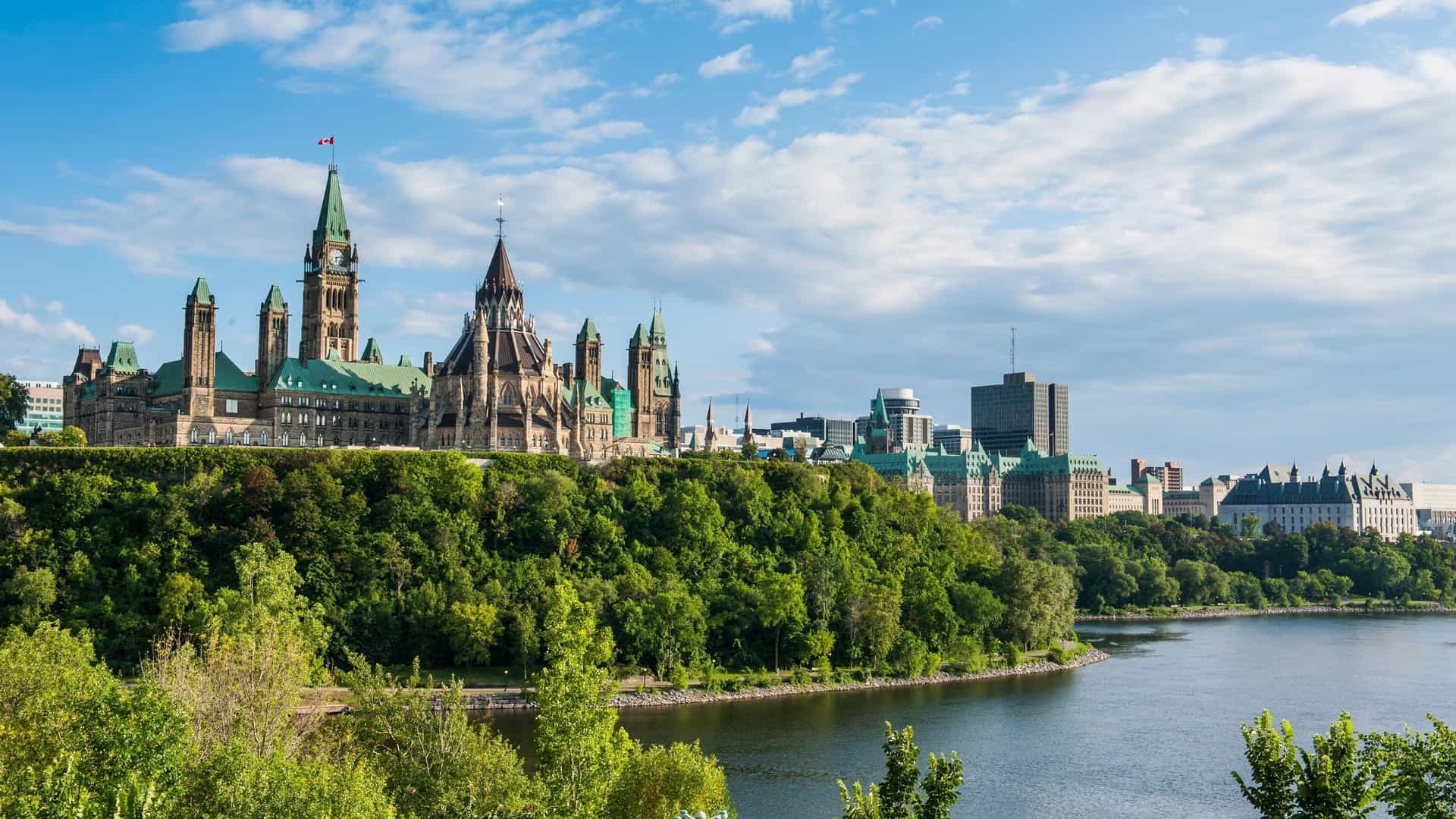 A beautiful panoramic shot of the Ottawa skyline and the Parliament Hill buildings, seen from across the Ottawa River, a landmark tourist destination.