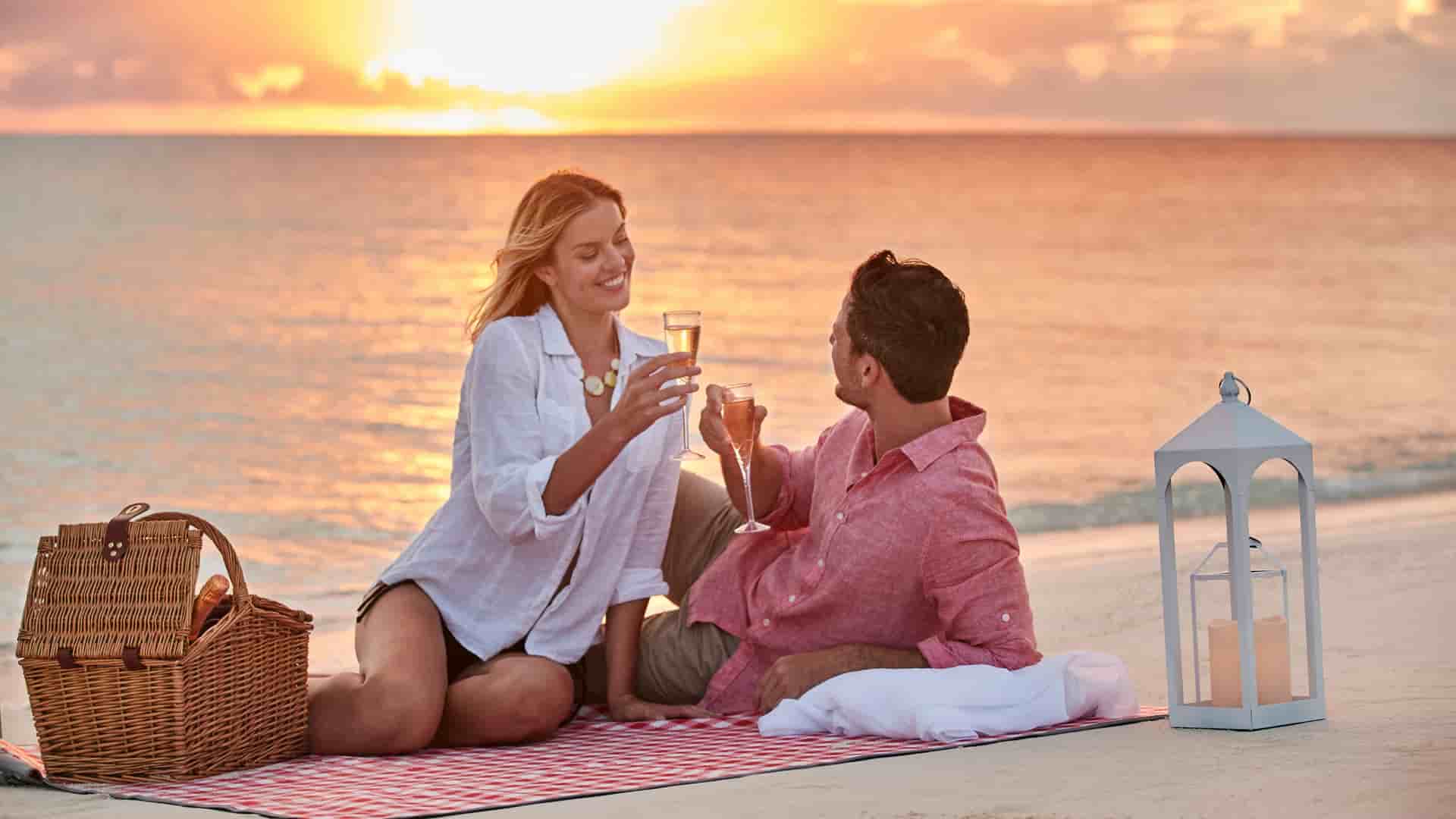 Couple enjoying on a picnic on a beach at sunset, and relaxing shore excursion on an MSC cruise.