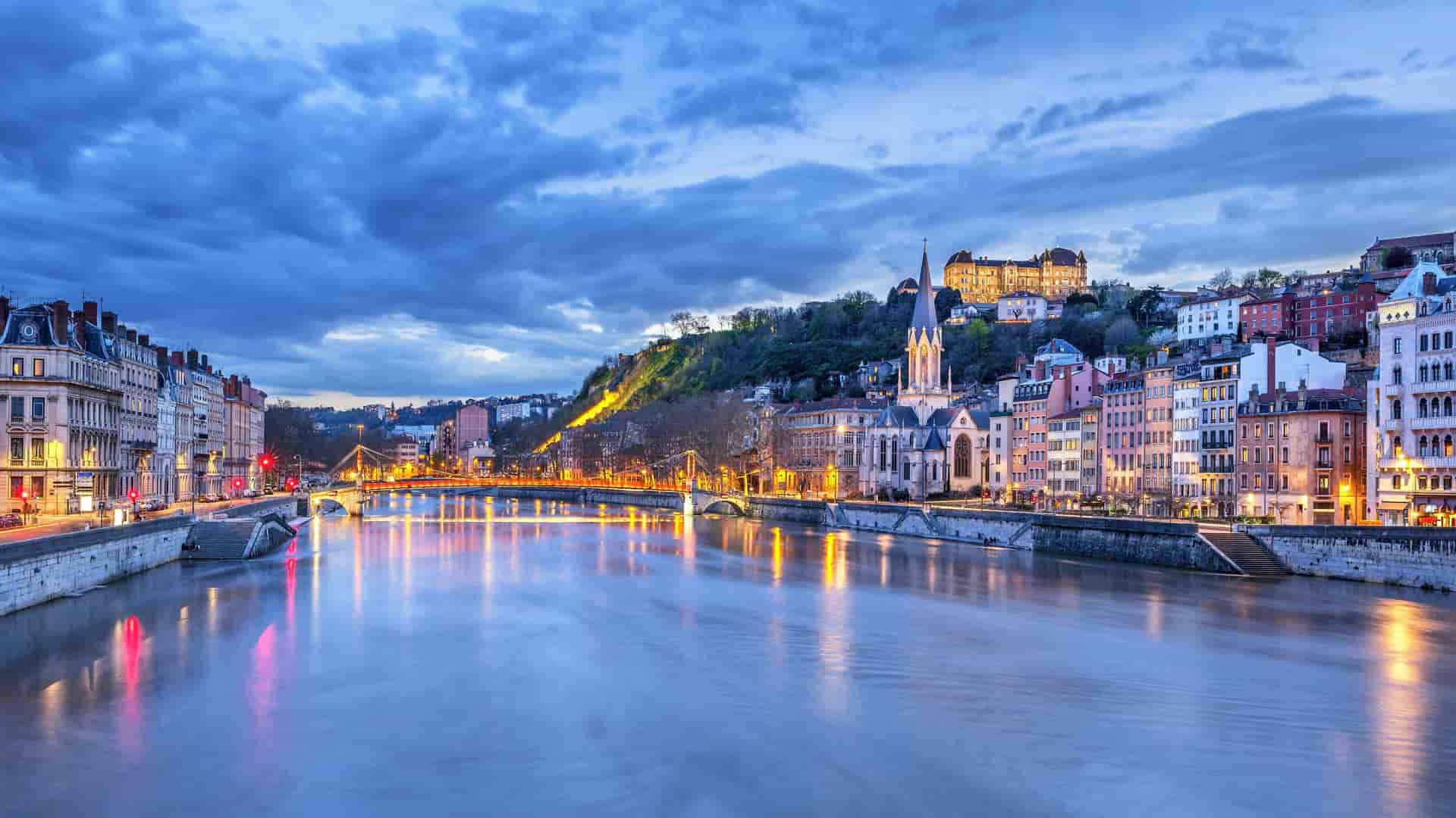 Evening skyline view of Lyon, France, with illuminated historic buildings lining the banks of the Saône River, a vibrant stop on AmaWaterways river cruises.