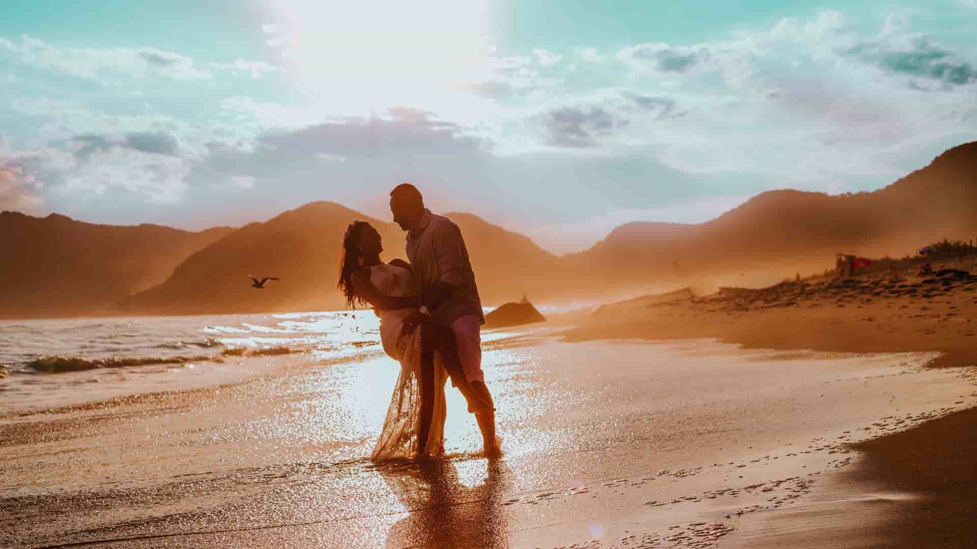 A smiling couple dancing on the beach on a warm summer day.