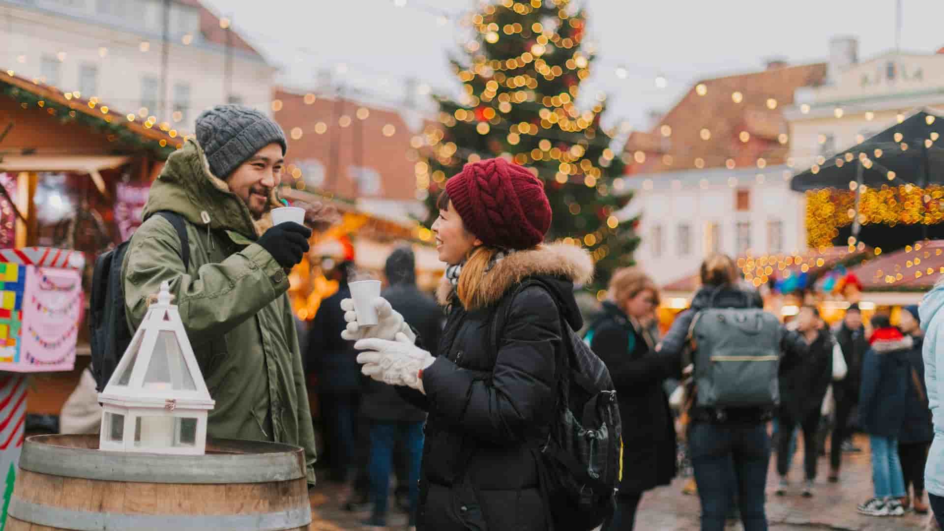 A couple happily trying mulled wine at an European Christmas Market during a cruise shore excursion.