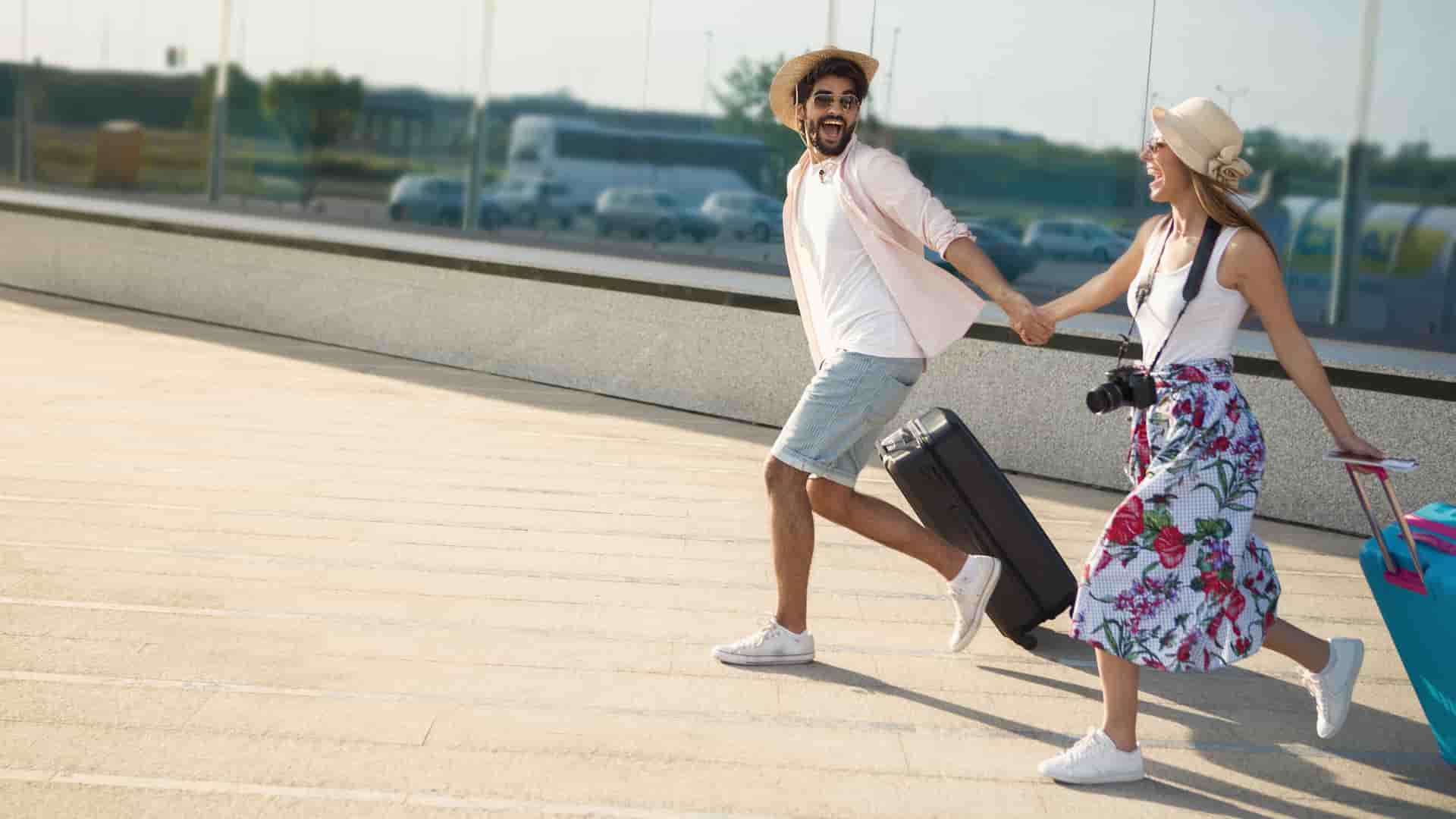 Excited couple running with their suitcases.
