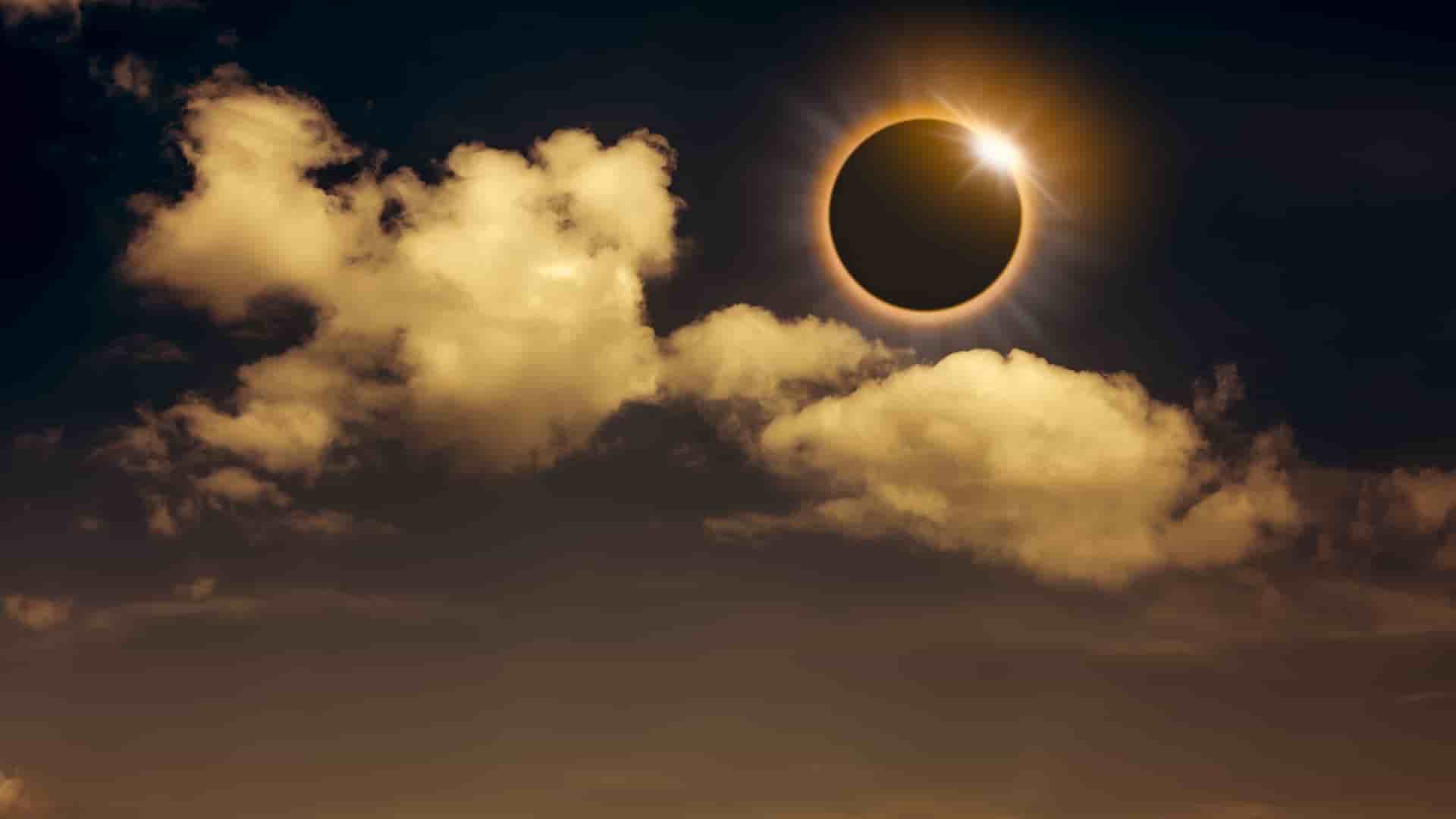 Partly cloudy sky during a full solar eclipse. 