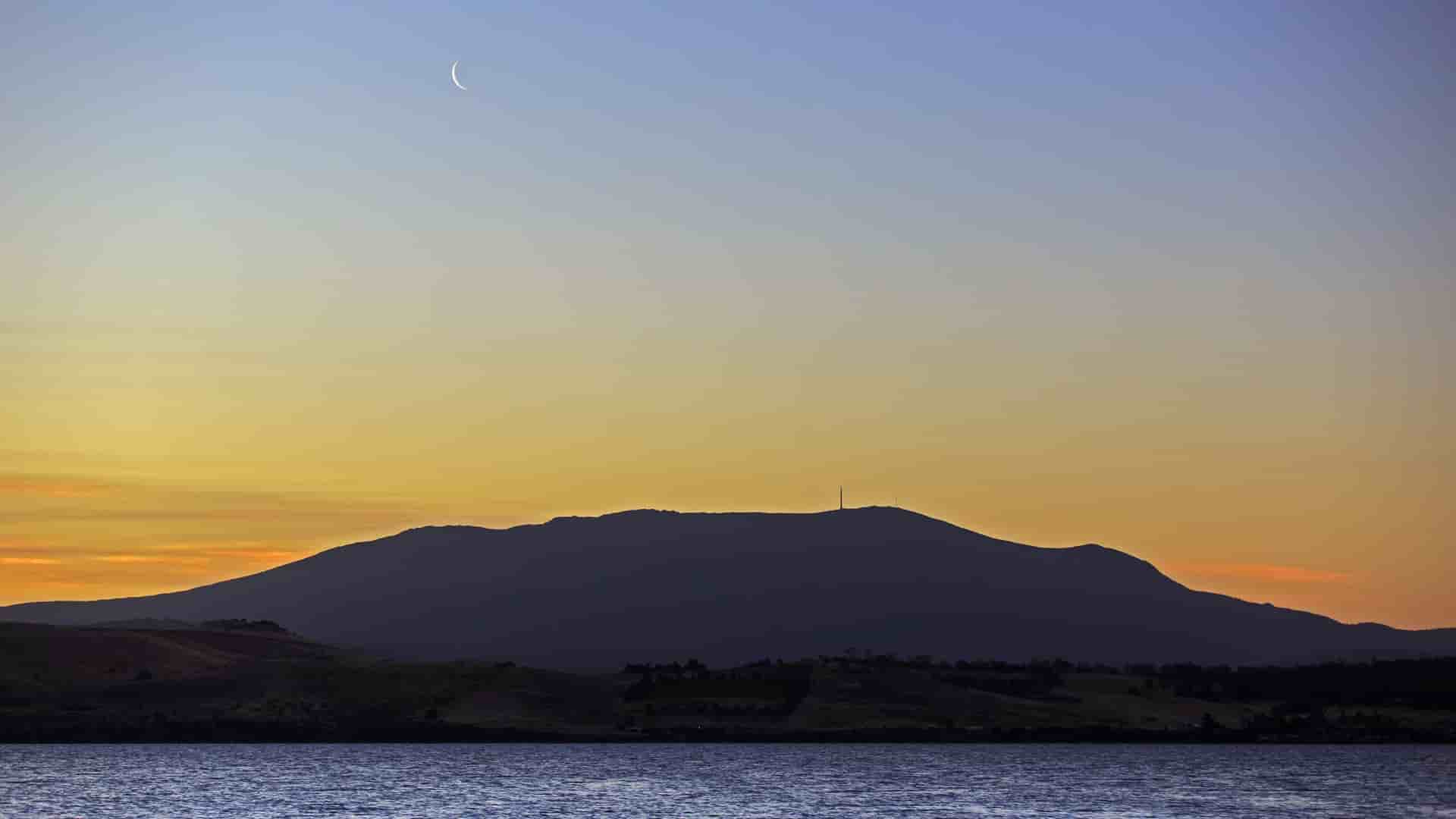 Hobart waterfront with boats and mountains.