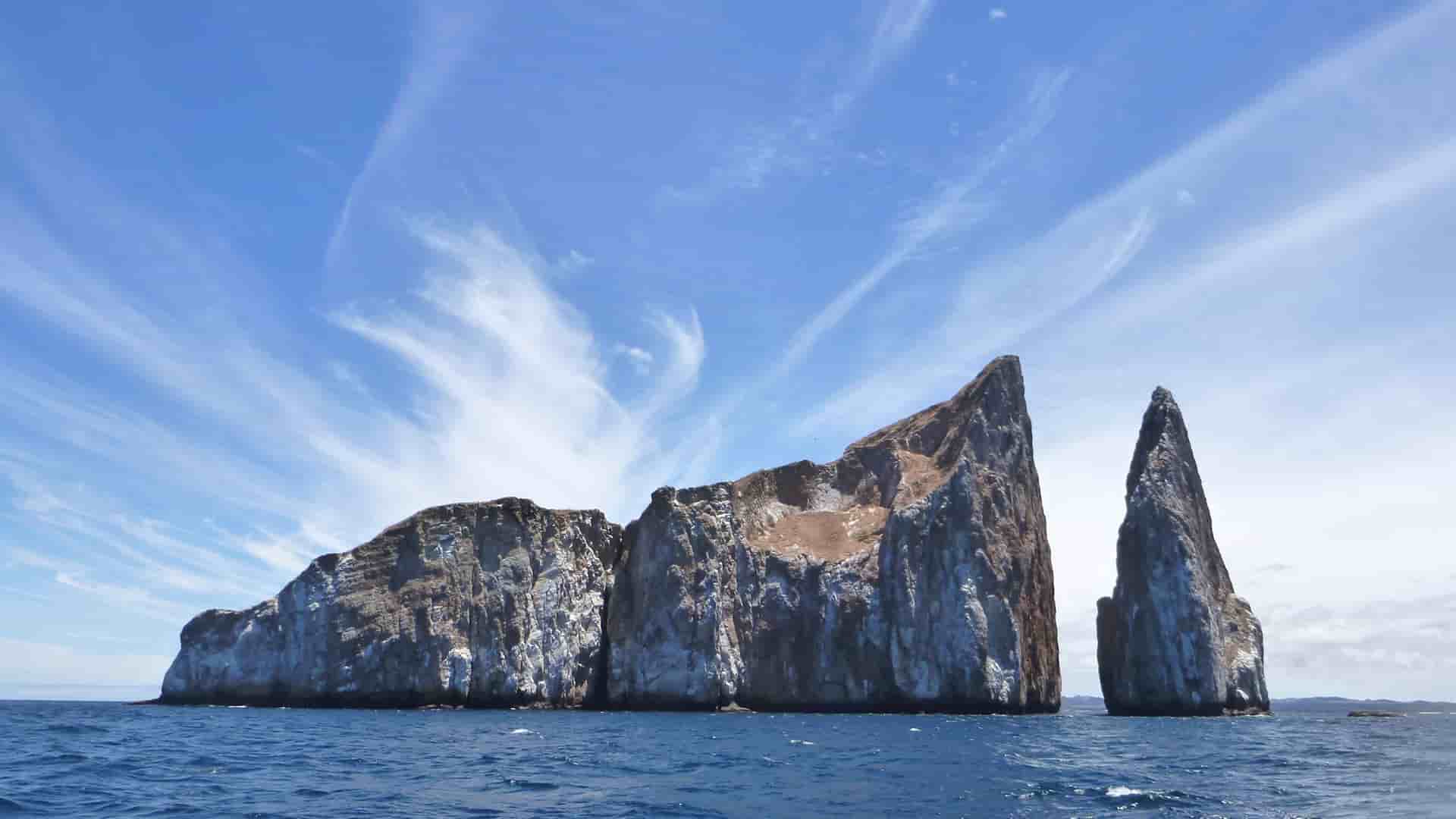 Kicker Rock (Leon Dormido) formation in Galapagos near San Cristobal Island under blue sky.