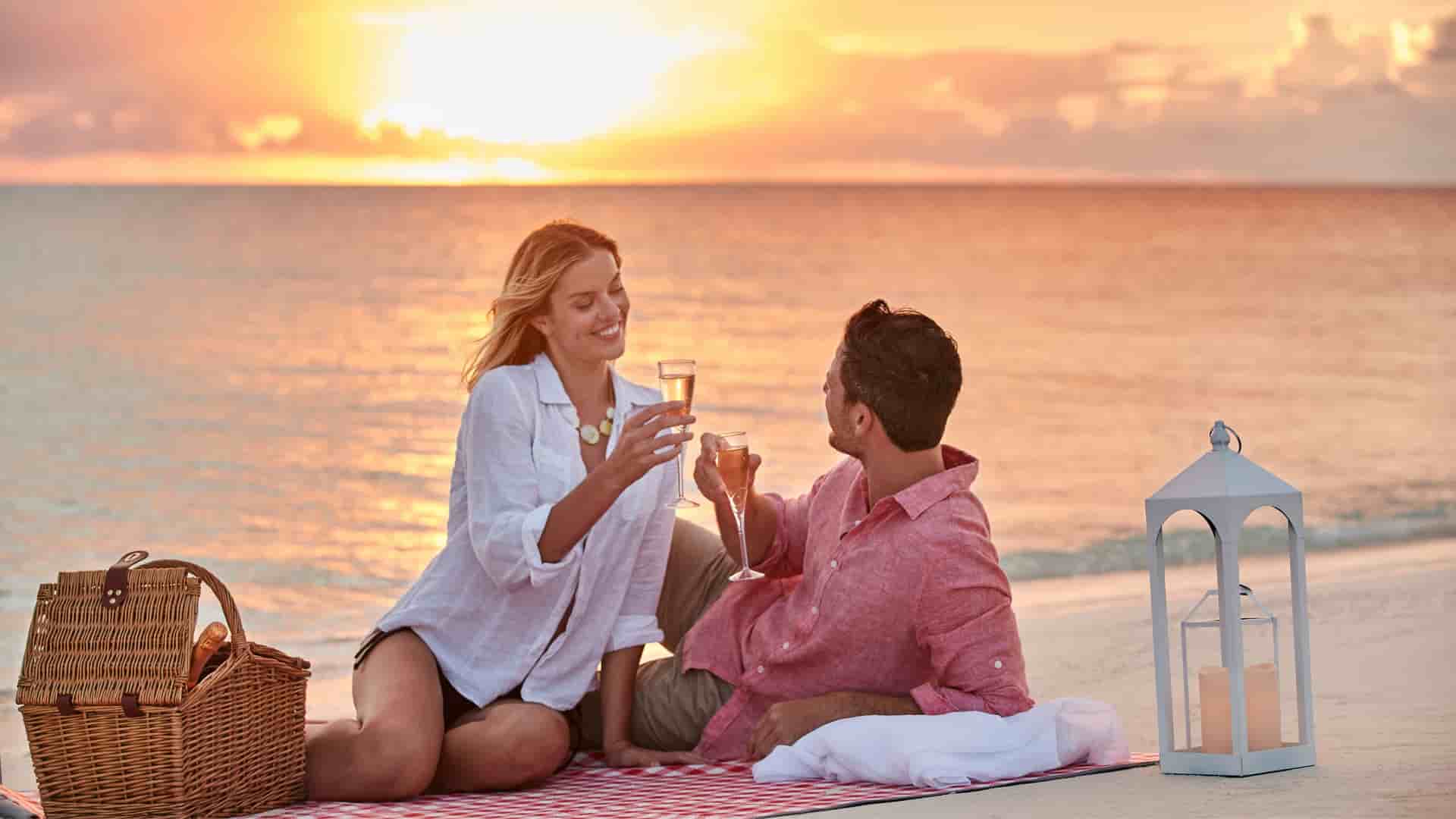 Couple enjoying a picnic on the beach at sunset during a MSC cruise.