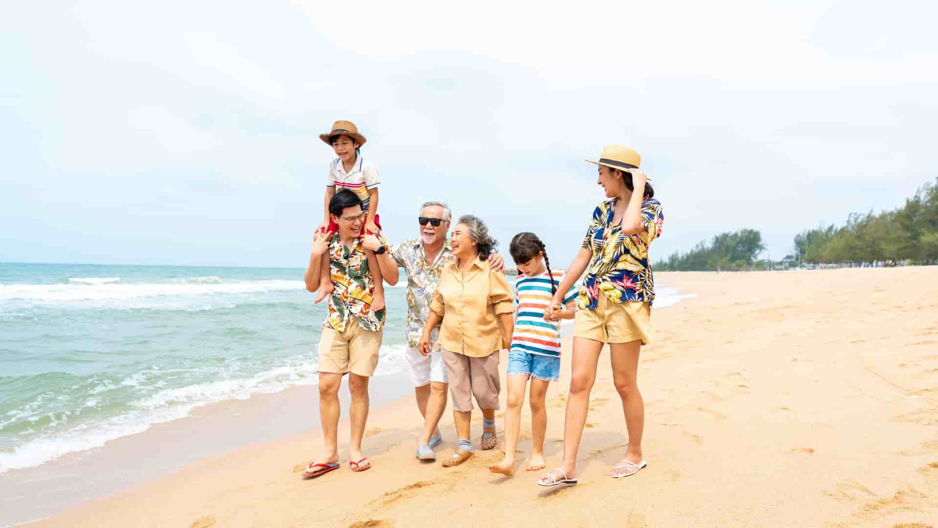Multi-generational family walking together along the beach.