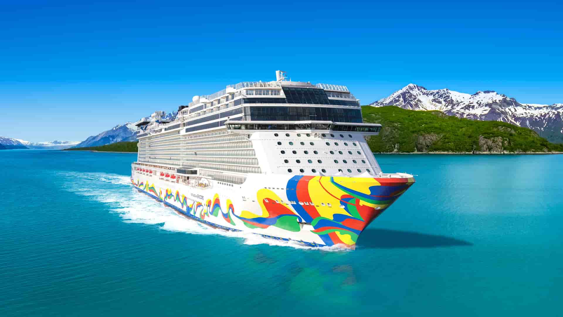 Norwegian Encore sailing past snow-capped mountains in Alaska.