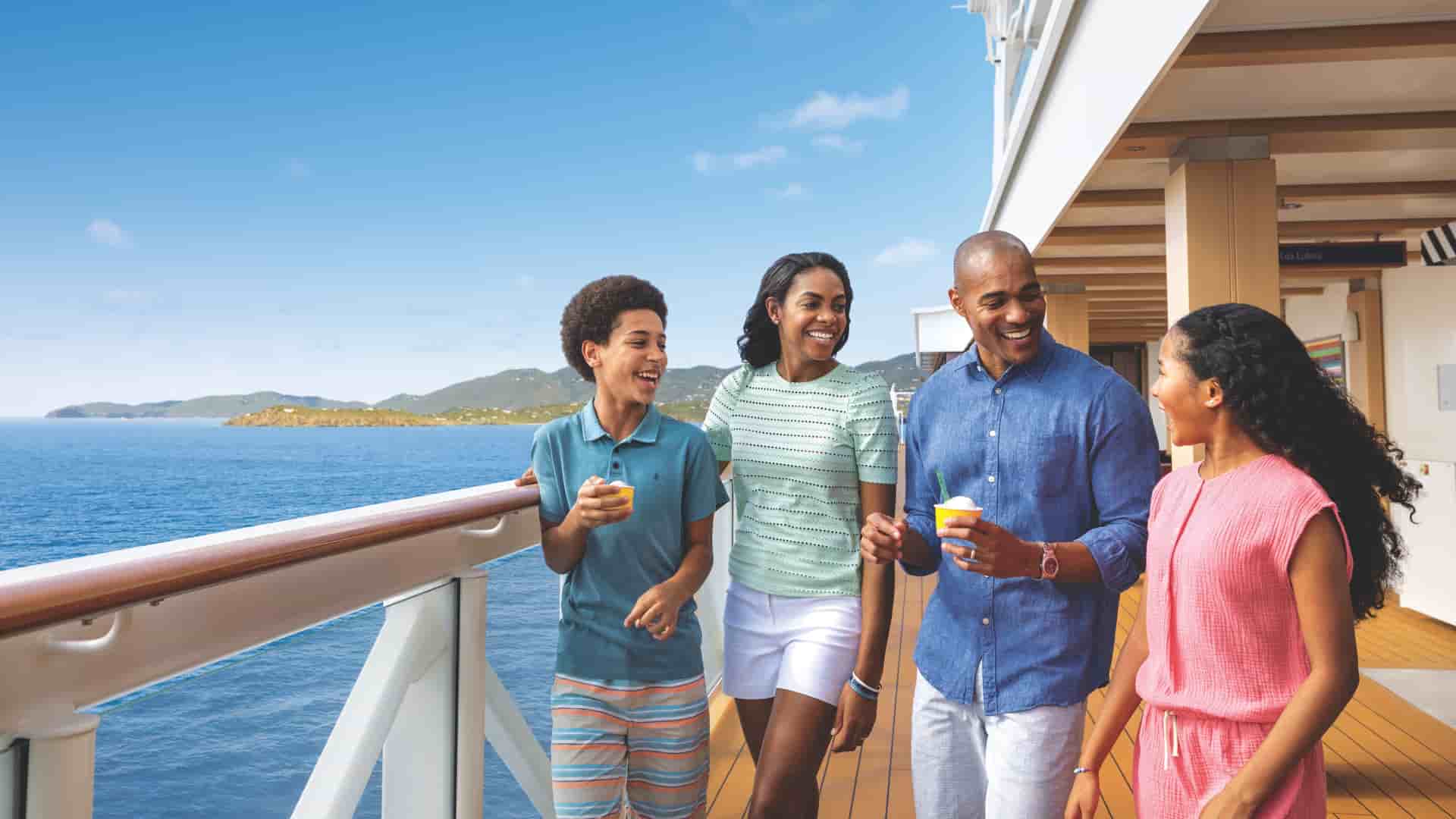 A family of four enjoying ice cream together while walking one of the decks of the Norwegian Encore cruise ship.