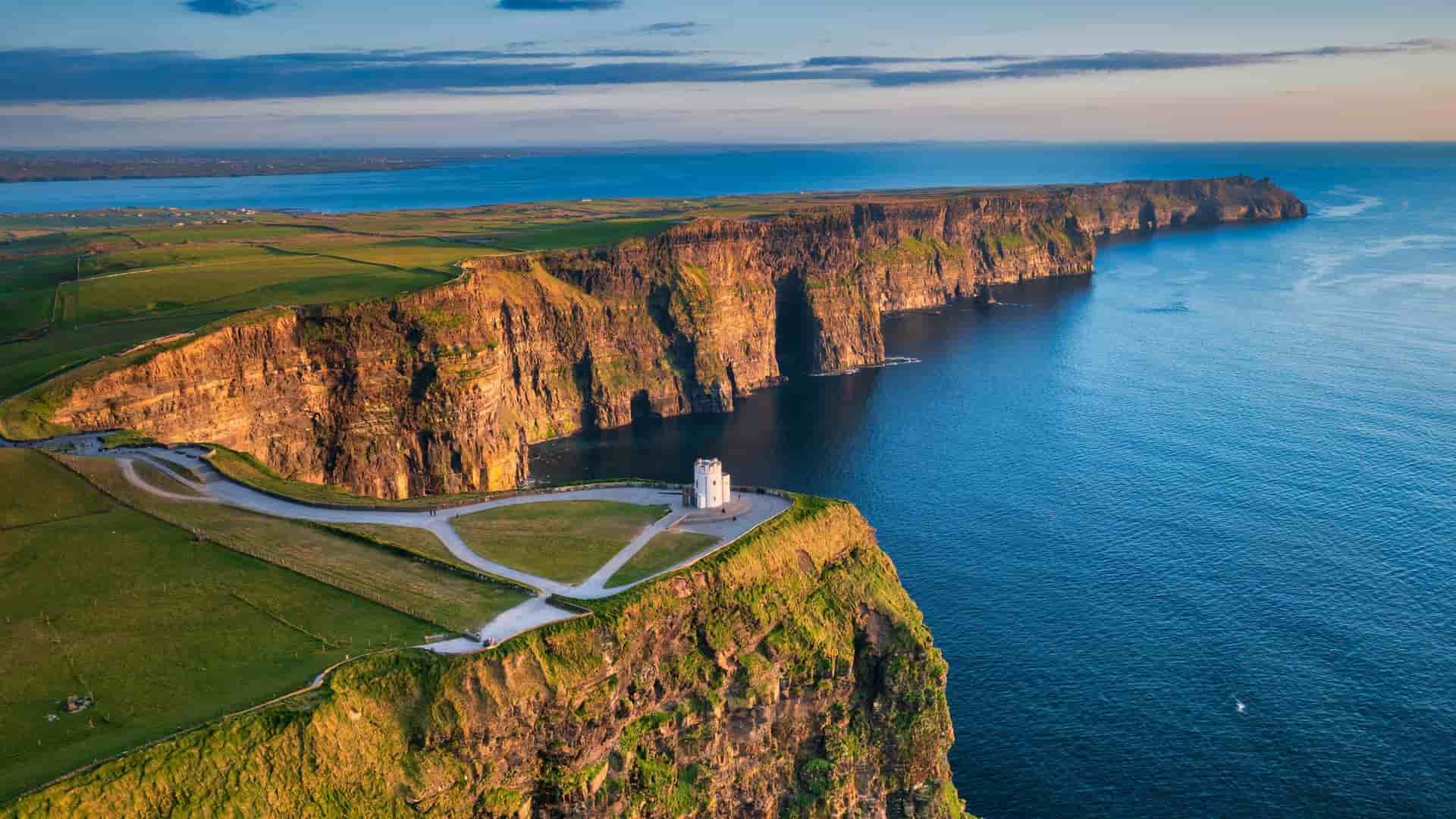 An aerial view of the iconic Cliffs of Moher in Ireland, showcasing the majestic cliffs towering over the Atlantic Ocean, with O'Brien's Tower visible on the edge.