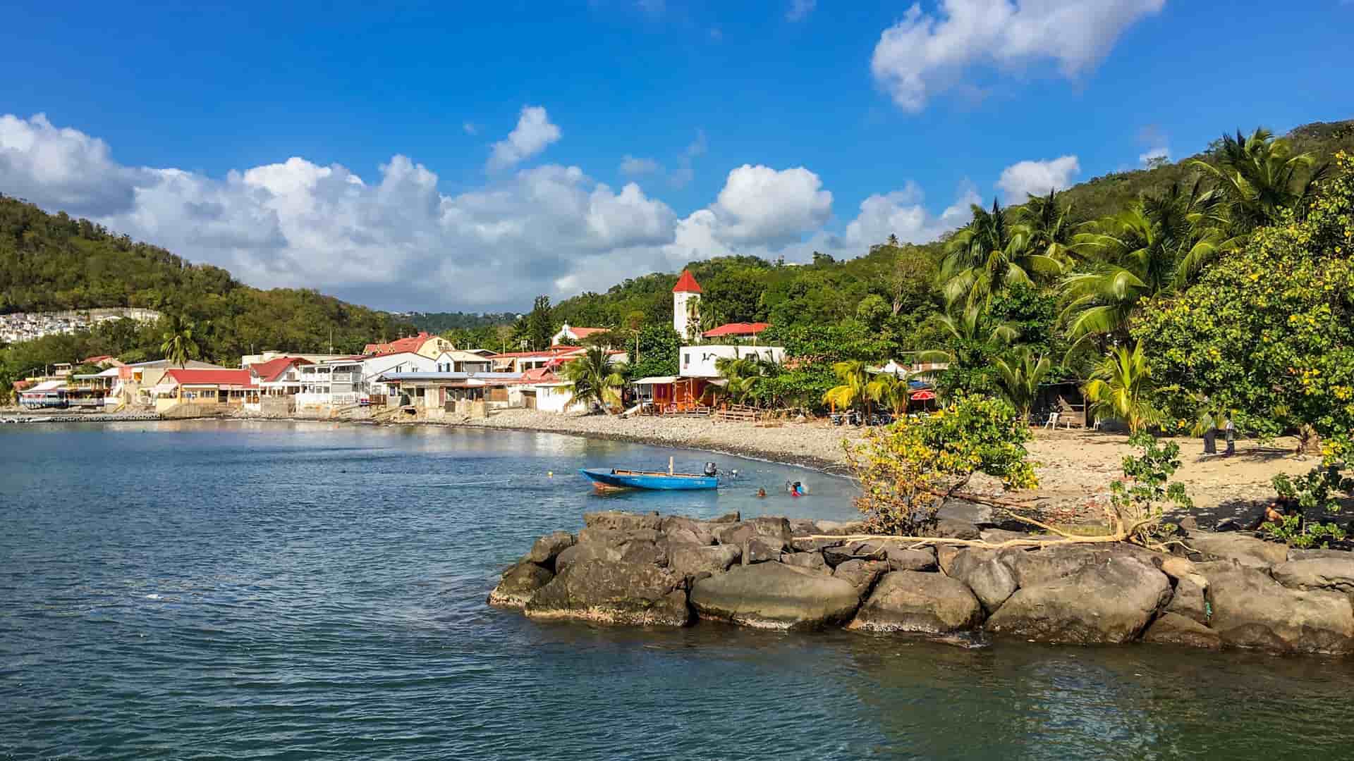 The picturesque fishing village of Deshaies, Guadeloupe, with its colorful waterfront and red-roofed church nestled on a tranquil bay.