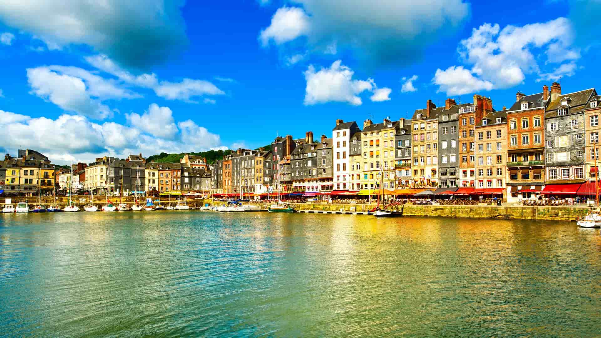 A beautiful scenic shot of the colorful, old-world houses and buildings lining the waterfront of the historic port of Honfleur, France.