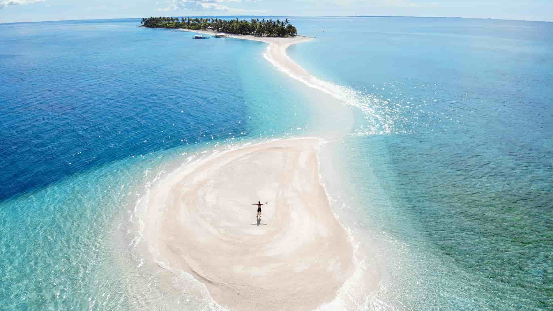An aerial view of the brilliant white sandbar extending from Kalanggaman Island, The Philippines, surrounded by clear blue water.