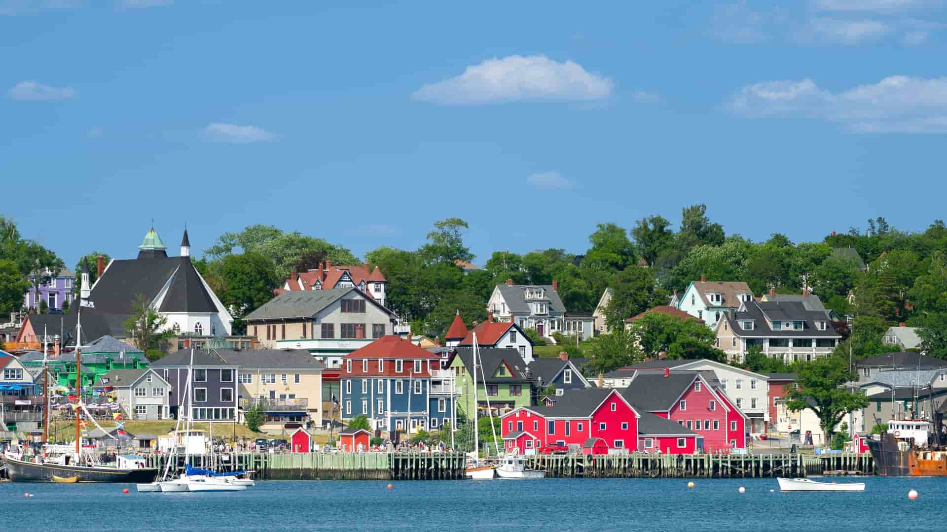 A scenic view of the waterfront in Lunenburg, Nova Scotia, with its colorful historic buildings and charming townscape, a designated UNESCO World Heritage site, on a sunny day.