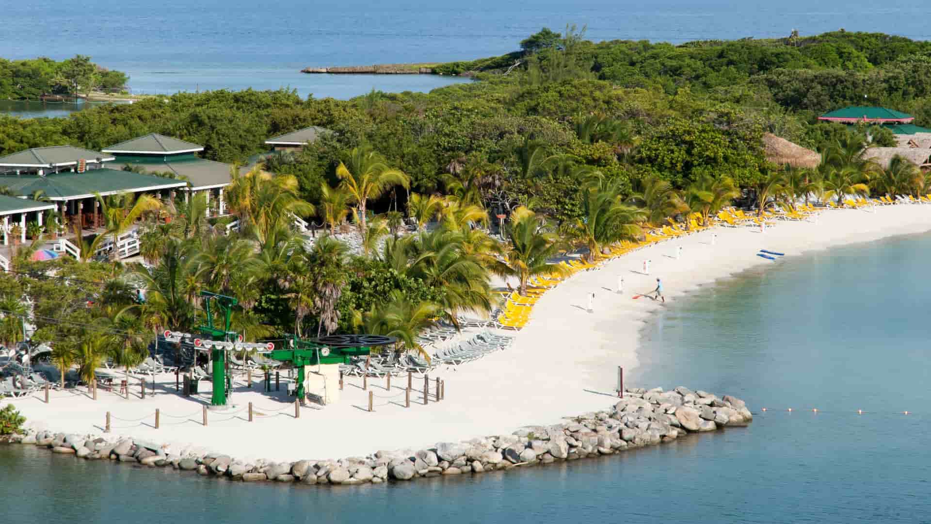A sunny shot of Mahogany Bay, Roatan, with white sandy beaches, green palm trees, a cruise ship port, and a chairlift.