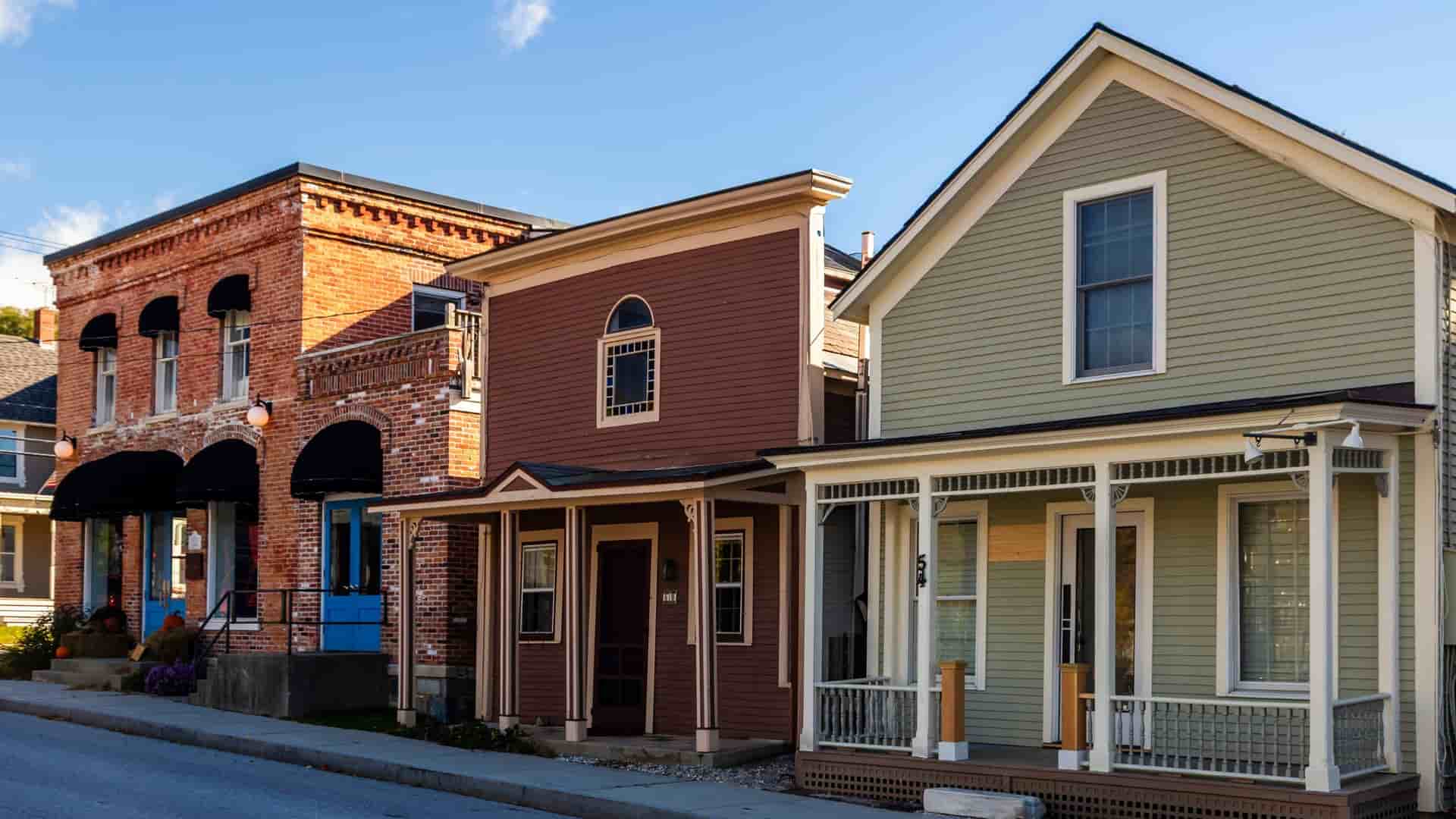 Historic, colorful buildings, including a brick facade and wooden houses with porches, line a street in Manchester, Vermont.