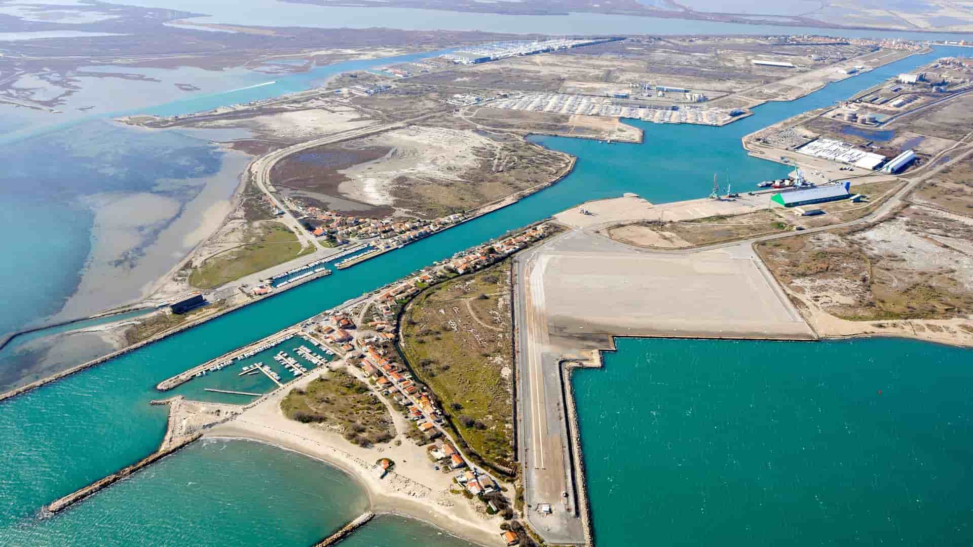 An aerial view of Port-Saint-Louis-du-Rhône, France, showcasing the Rhône River delta and the industrial port area next to the town and its marina.