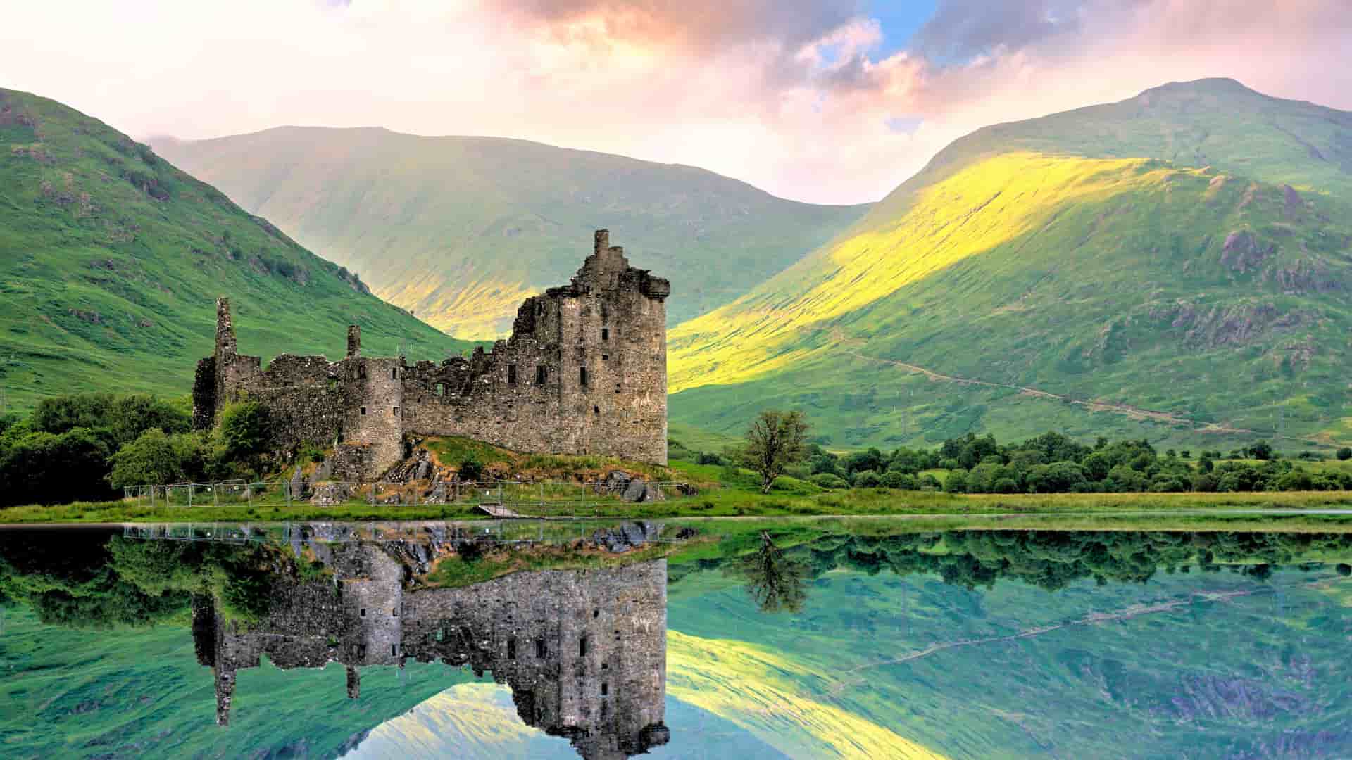 "A dramatic landscape of the Scottish Highlands, with the medieval ruins of Kilchurn Castle and its reflection in the calm, green water of Loch Awe, surrounded by lush, rolling mountains.  "