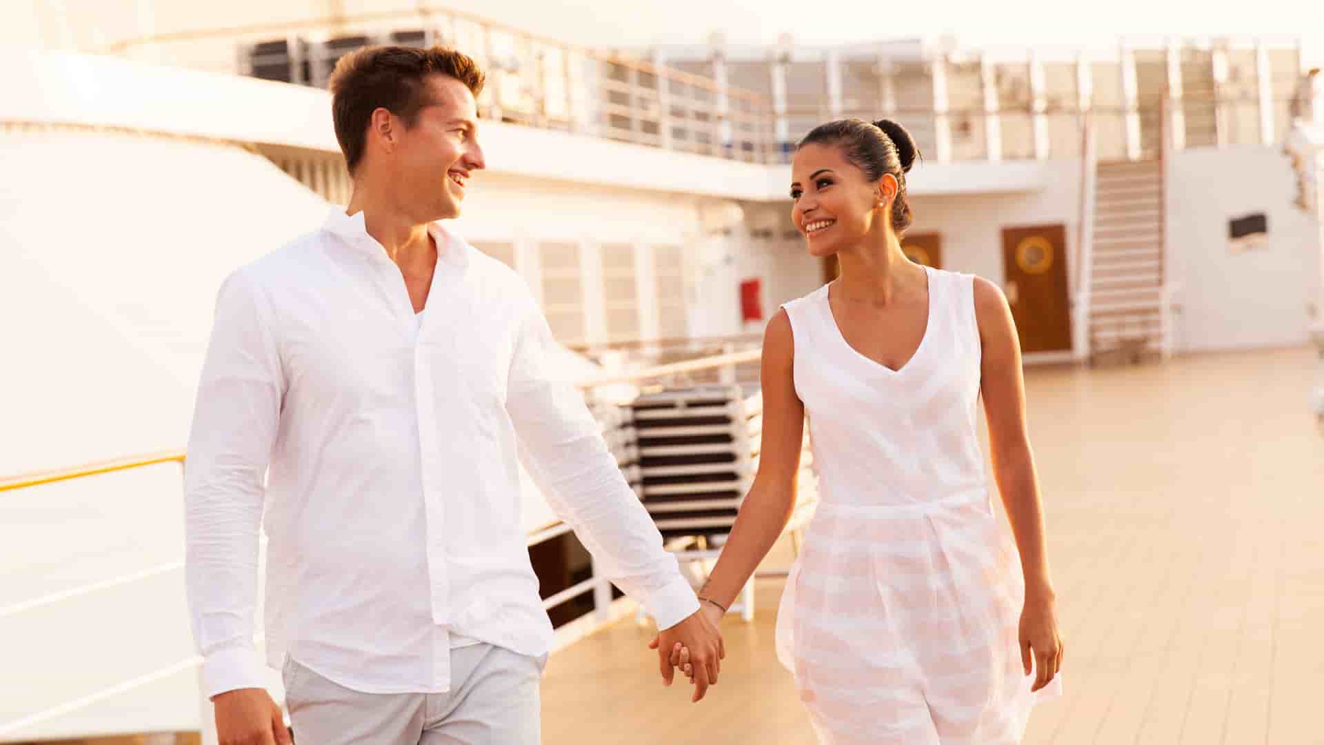 Young couple walking and holding hands on a top deck during their romantic cruise.jpg