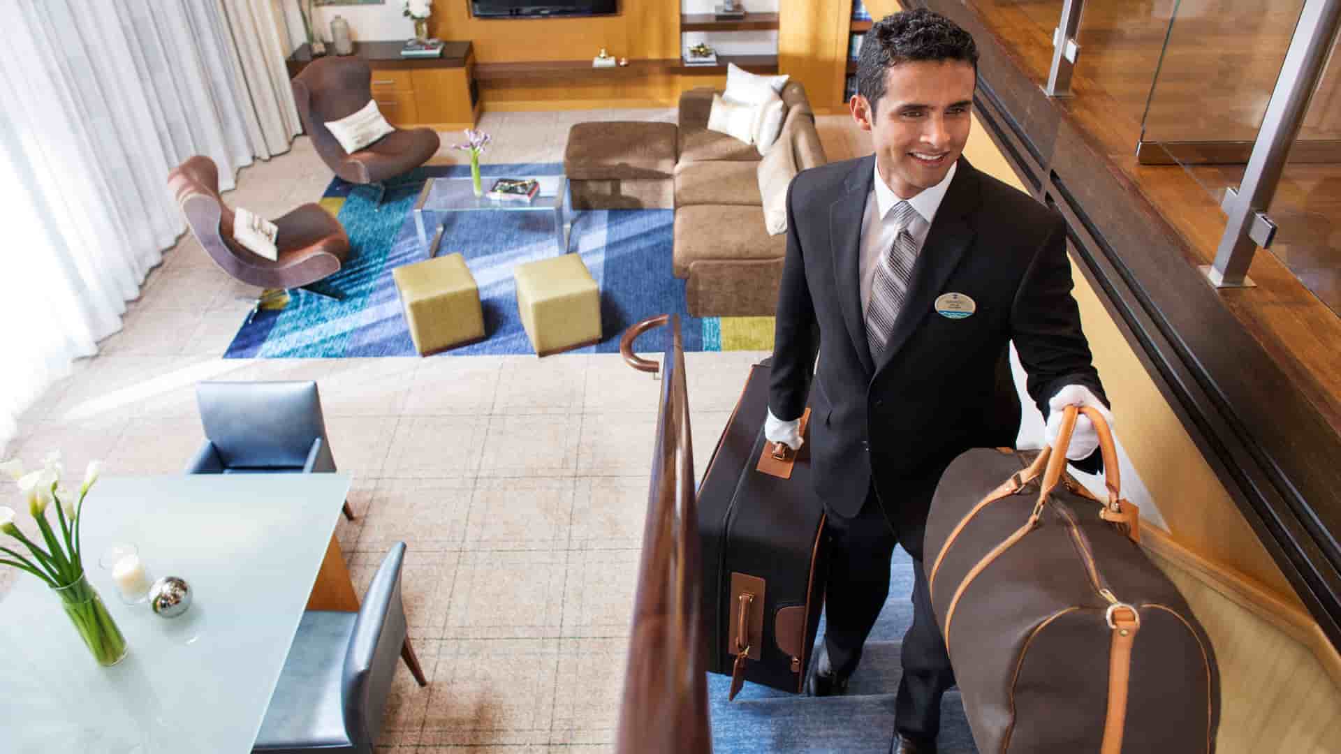 A Royal Genie personal assistant carrying luggage up the stairs on a Royal Caribbean cruise.