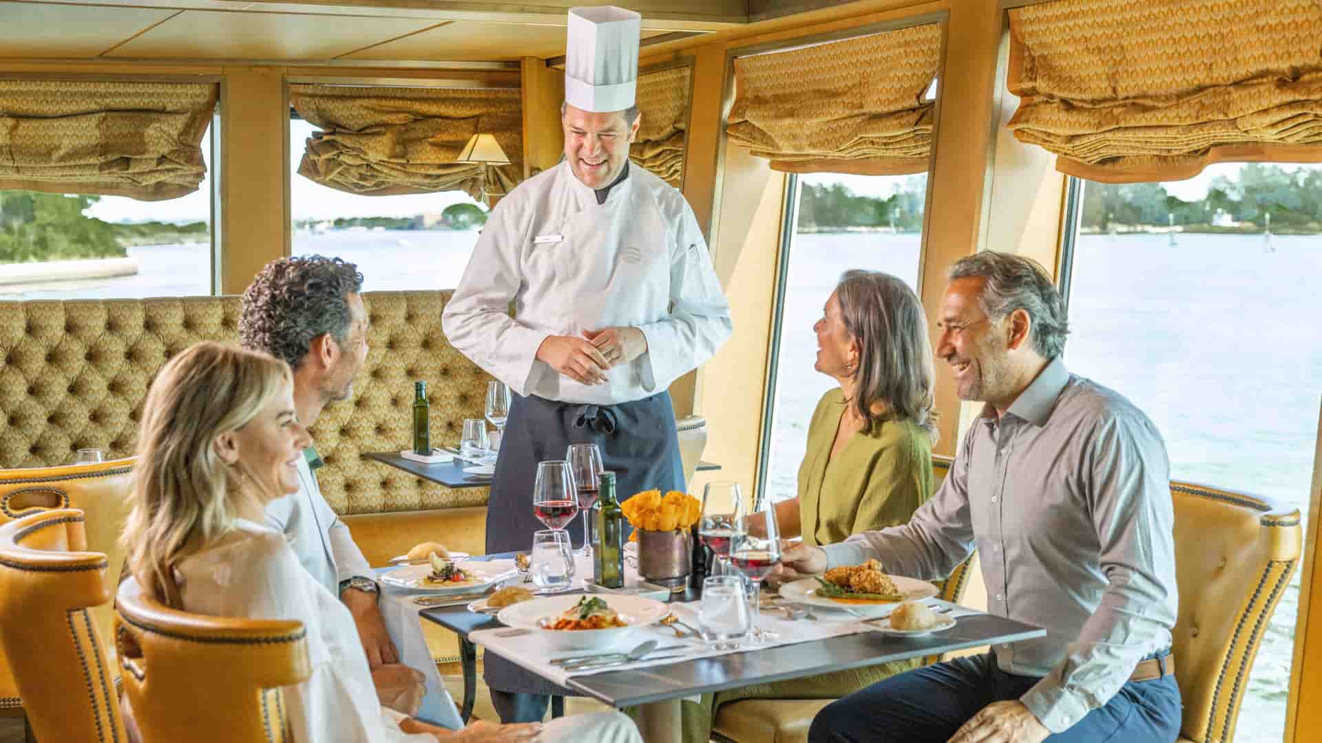 Head Chef talking with 2 couples dining at Ristorante Rialto onboard the S.S. La Venezia.