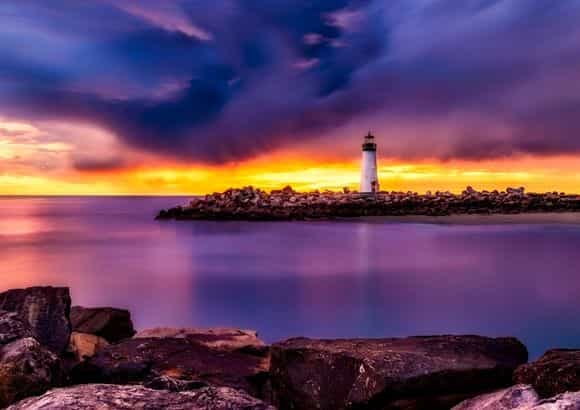 Lighthouse in New England and Canada with vibrant purple and orange skyline.