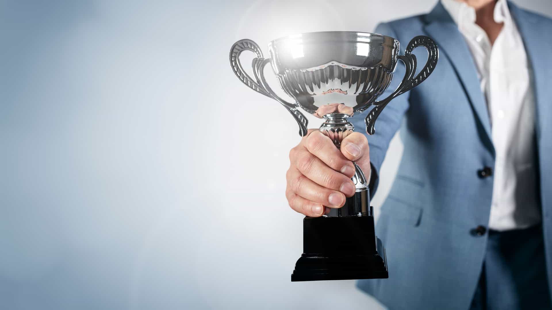 A businessman stands with a trophy award in hand, showcasing his success and accomplishment.