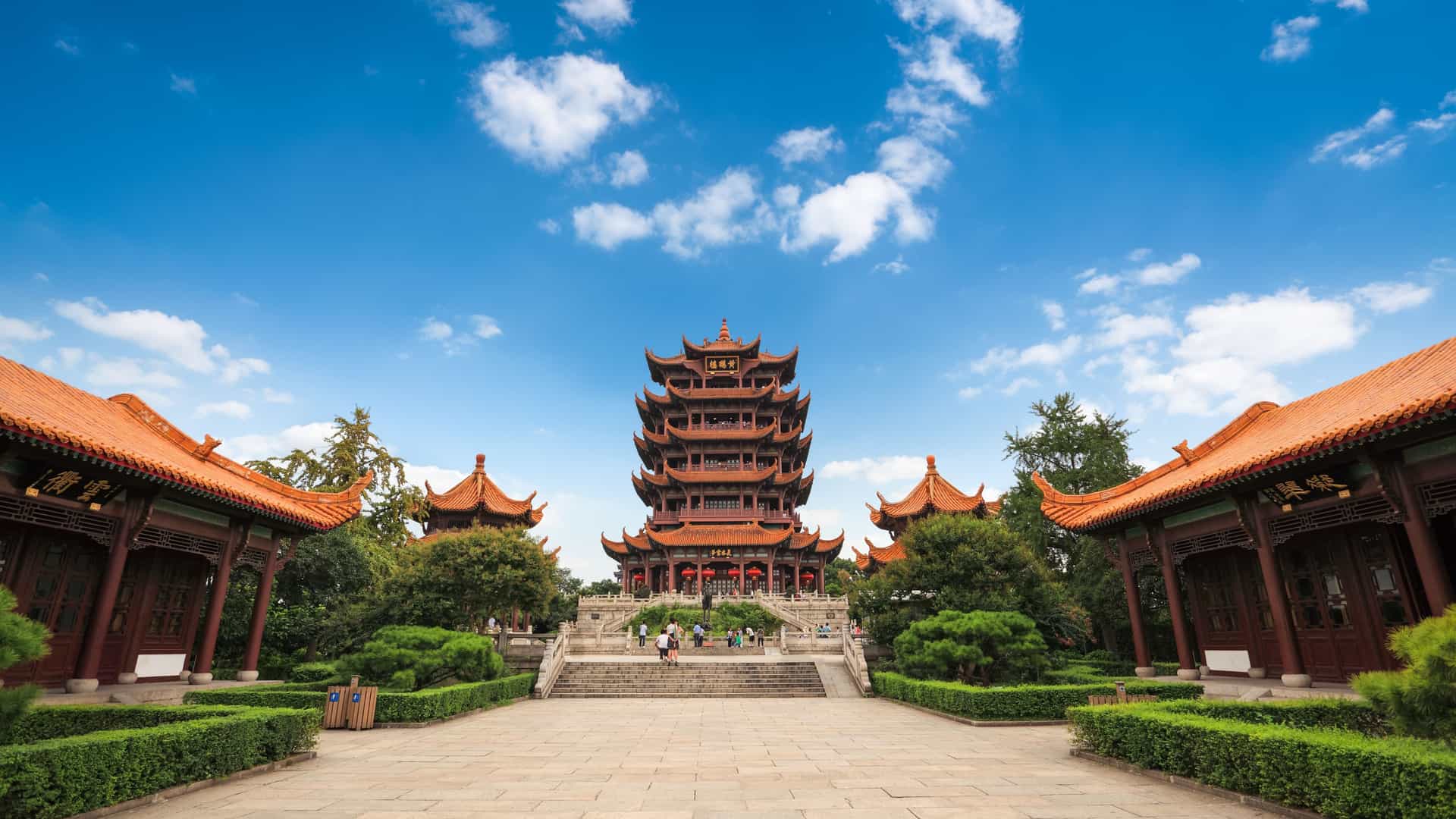 The iconic Yellow Crane Tower rises above lush gardens in Wuhan, China—its multi-tiered pagoda design a highlight of Carnival Cruises’ Asia itineraries.