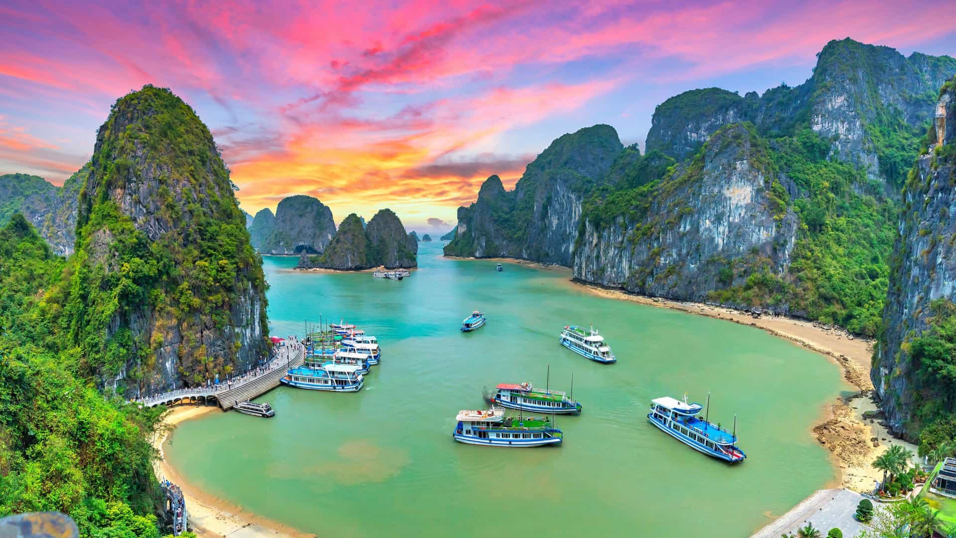 Sunset over Ha Long Bay, Vietnam, with traditional boats and limestone karsts; a breathtaking Carnival Southeast Asia cruise destination.