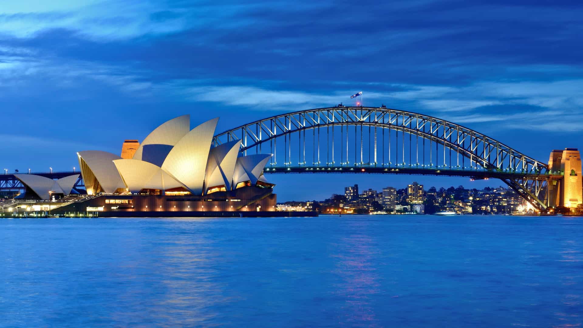 Sydney Harbour at night with glowing Opera House and Harbour Bridge—signature views from Carnival Cruises in Australia and New Zealand.