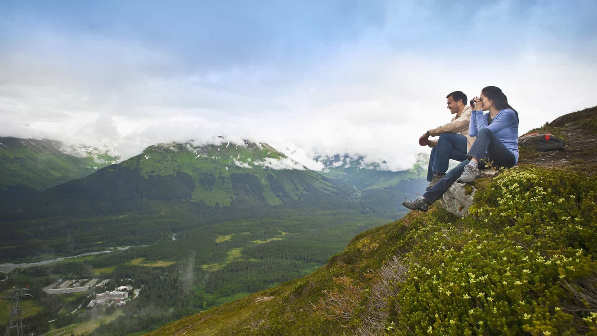 Couple enjoying a vast Alaskan mountain view, highlighting Celebrity Cruises' immersive excursions.