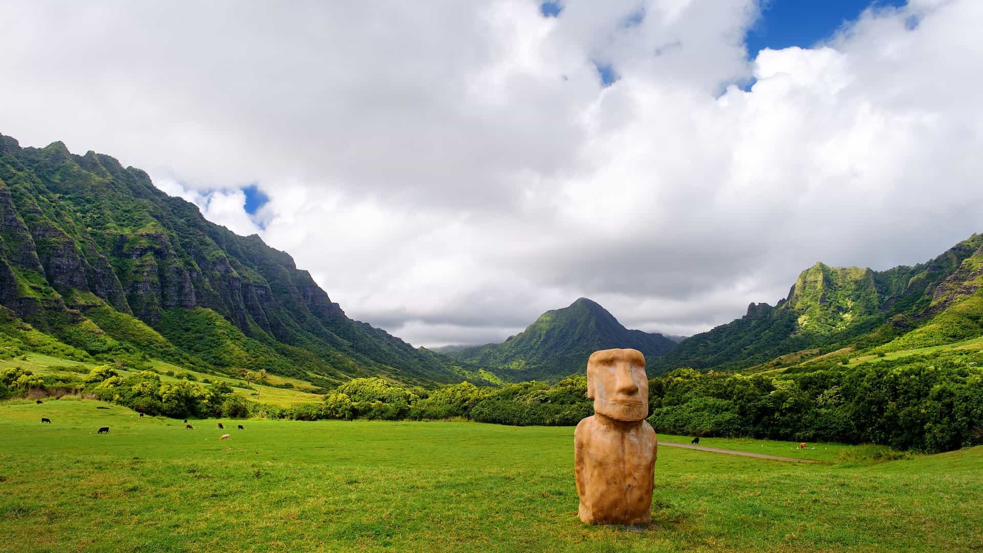 Replica Moai statue in a green valley at Kualoa Ranch, Oahu, with mountains in the background on a Celebrity Cruises Hawaiian voyage.