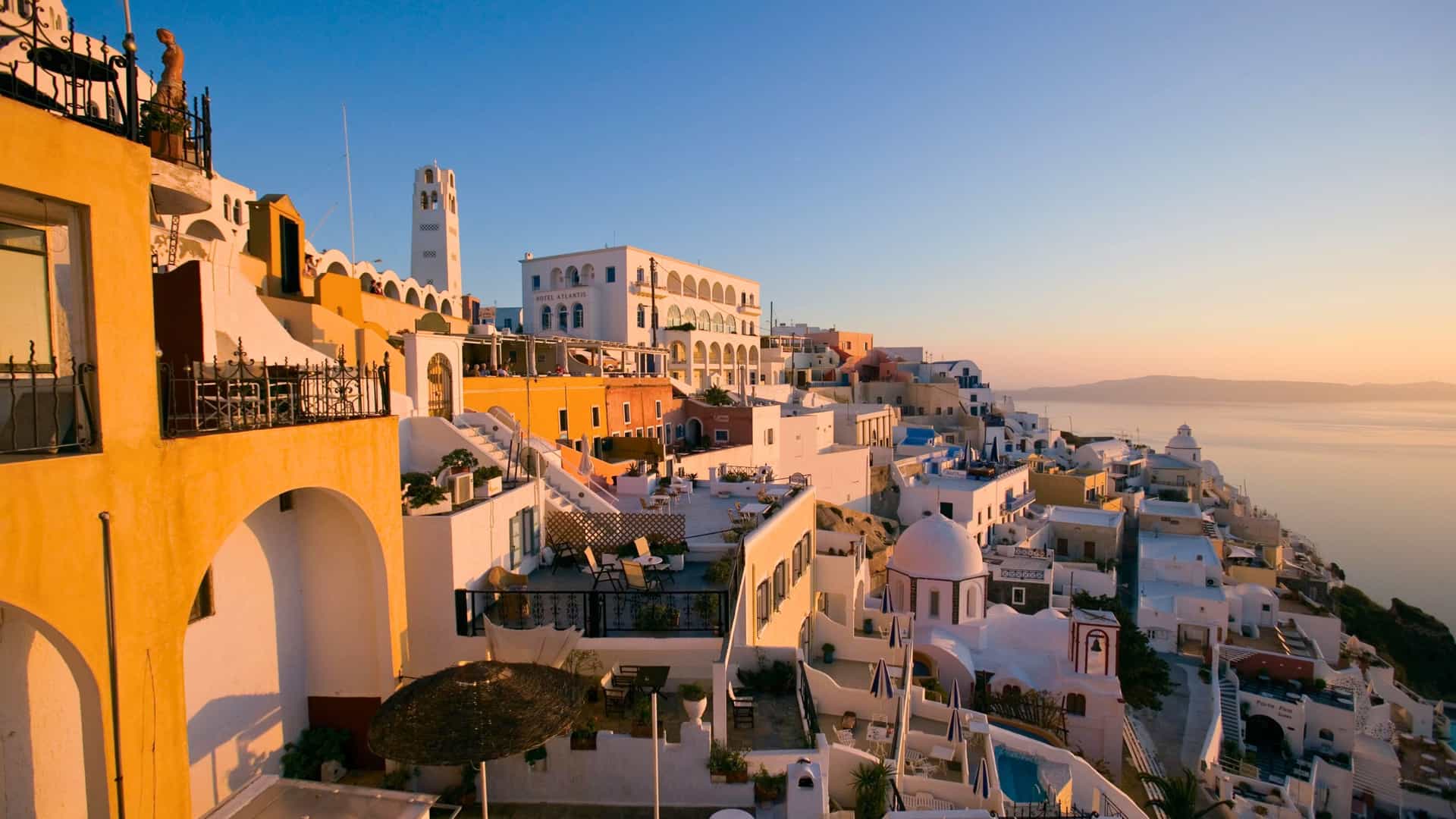 White cliffside buildings in Fira, Santorini overlooking the Aegean Sea at sunset on a Celebrity Cruises Mediterranean itinerary.