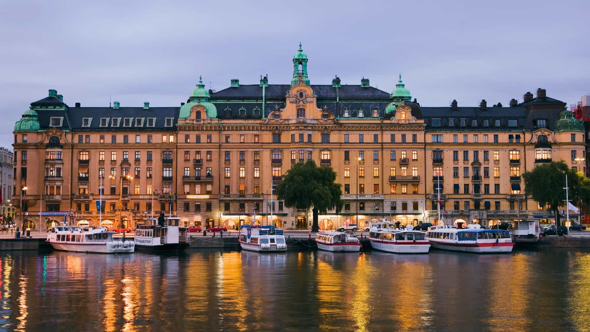 Stockholm’s Skeppsbron waterfront at dusk with boats and reflections on a Celebrity Cruises Northern Europe itinerary.