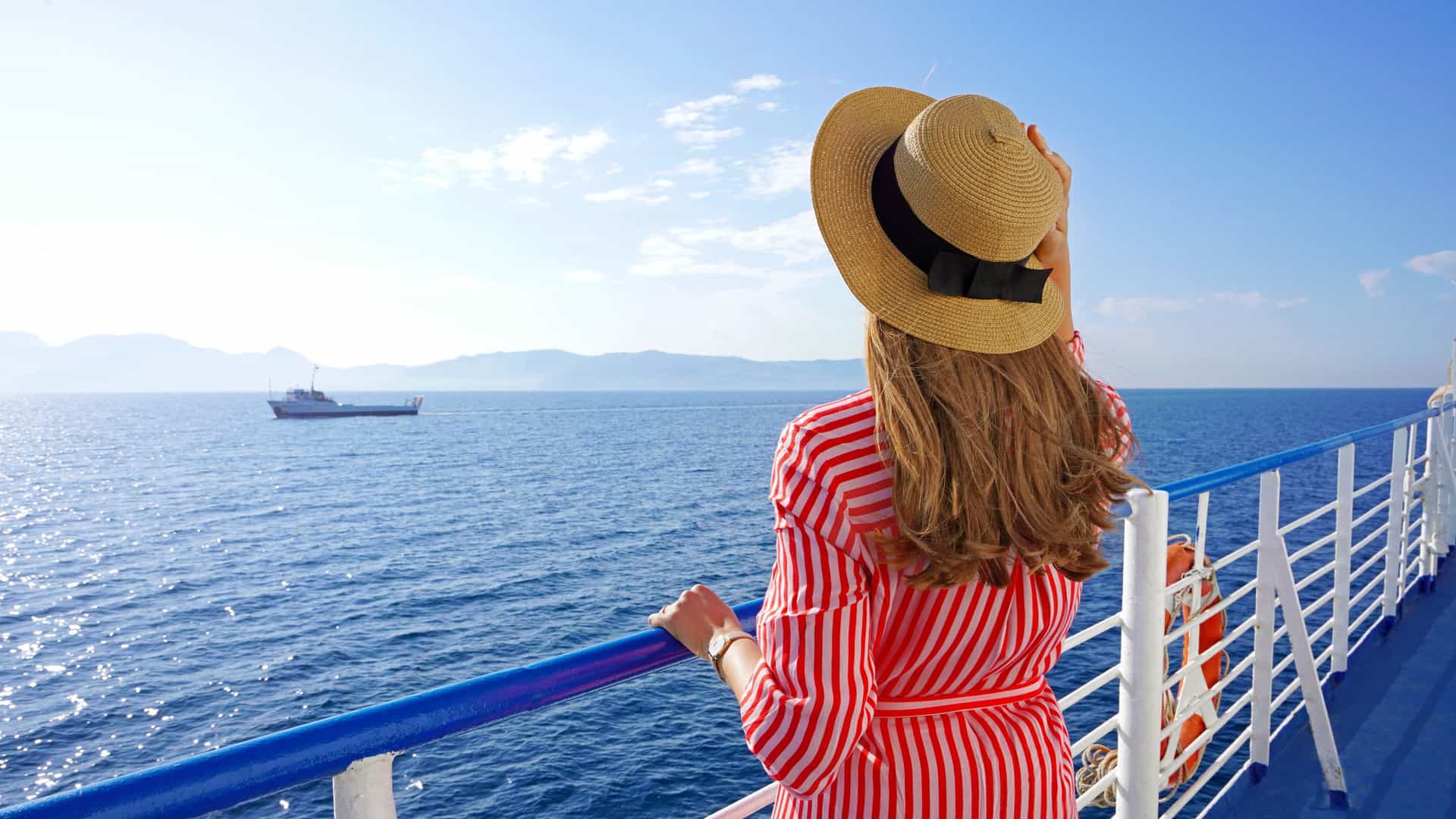 Woman in a straw hat on deck of a Celebrity Cruises ship looking out at the Pacific Ocean during a Trans-Pacific crossing.