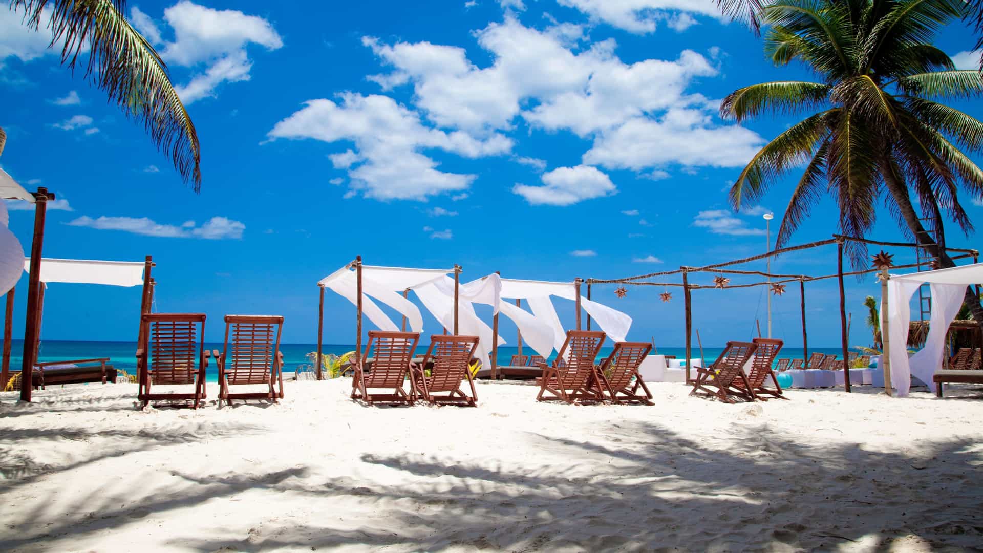Tulum beach with chairs and palm trees, highlighting Celebrity Cruises' Caribbean voyages.