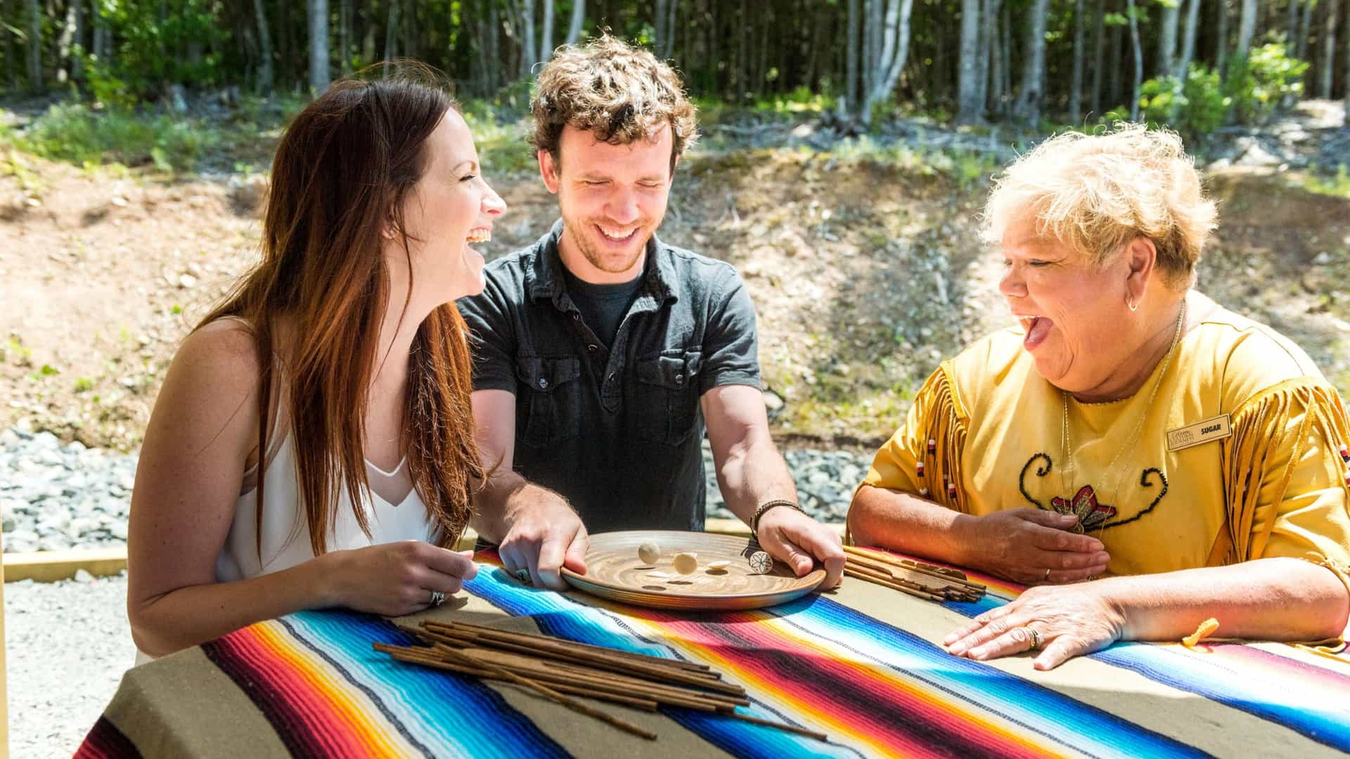 A couple sitting at a table learning and enjoying an Eskasoni cultural excursion.
