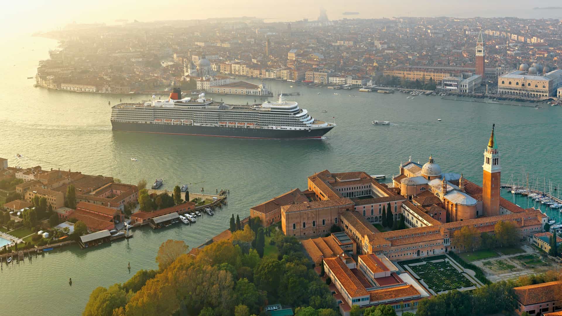 Aerial view of a Cunard cruise ship docked in Venice, Italy, showcasing the city's timeless charm and the elegance of a European luxury voyage.