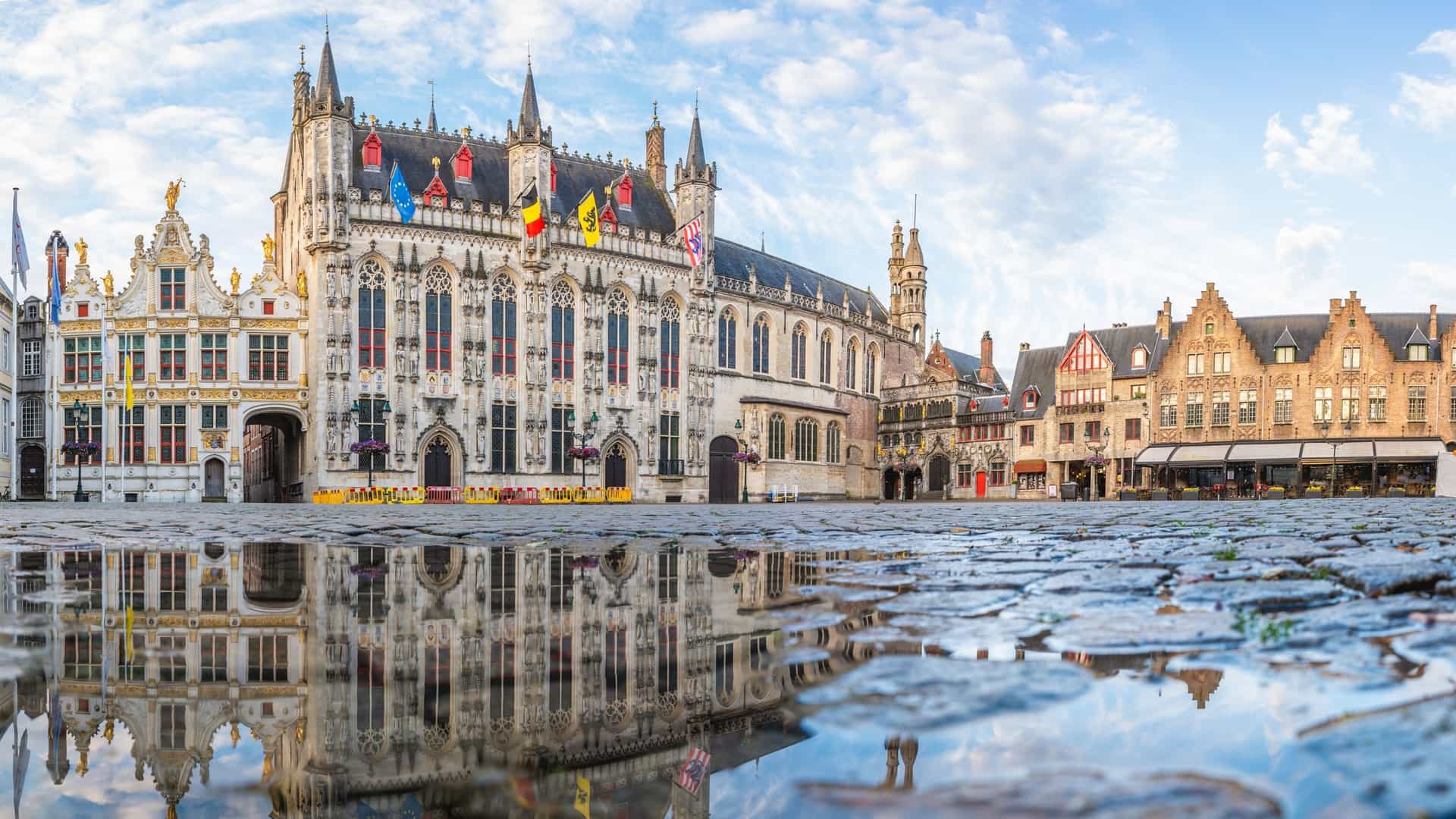 The Burg Square (Burg Plein) in Bruges, Belgium, showcasing the ornate Gothic facade of the Bruges City Hall (Stadhuis) and the neighboring Basilica of the Holy Blood (Heilig-Bloedbasiliek).