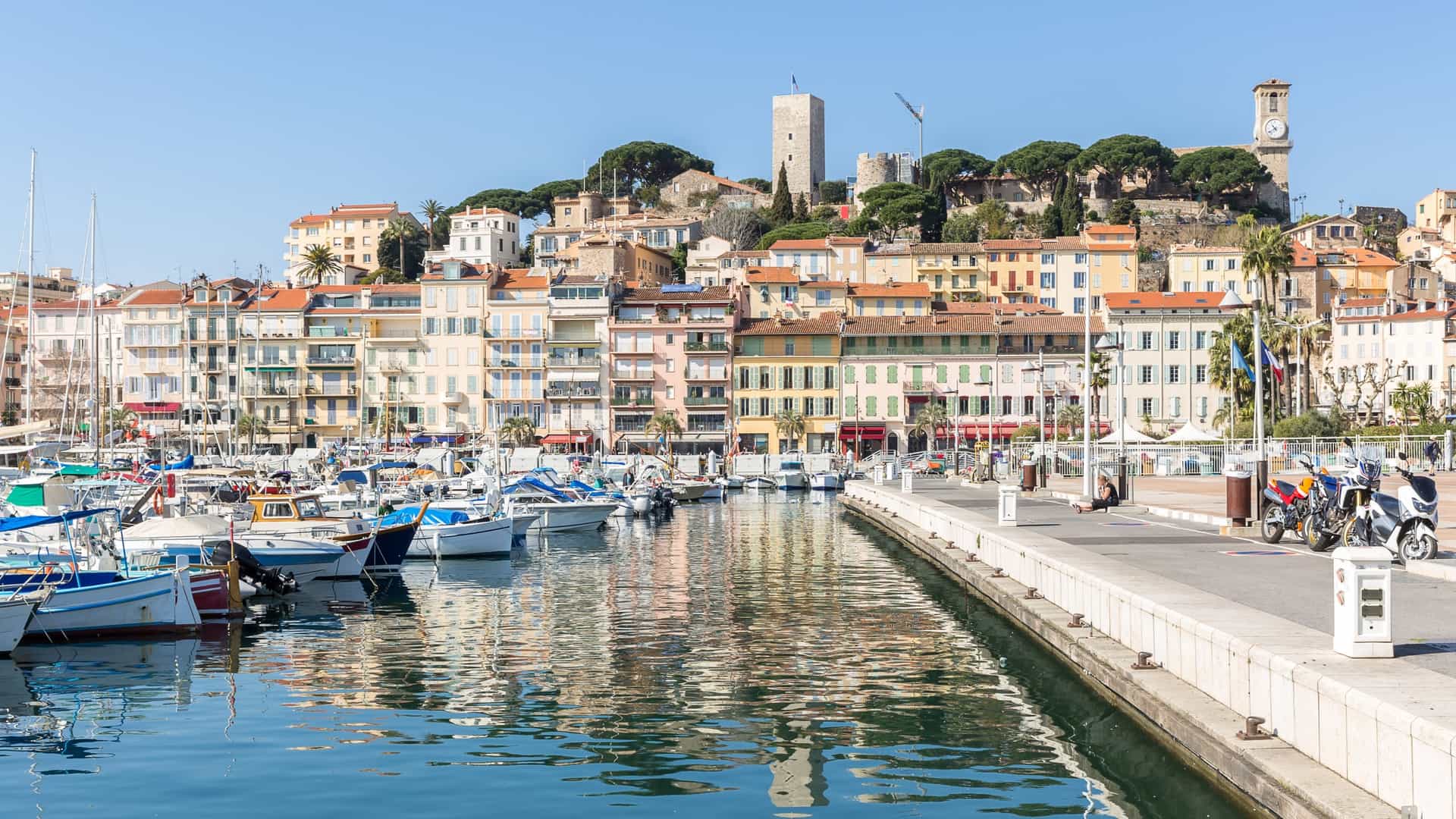 A view of Le Suquet, the historic Old Quarter of Cannes, France, featuring its narrow, cobbled streets and the colorful facades of the traditional buildings leading up to the hill's summit.