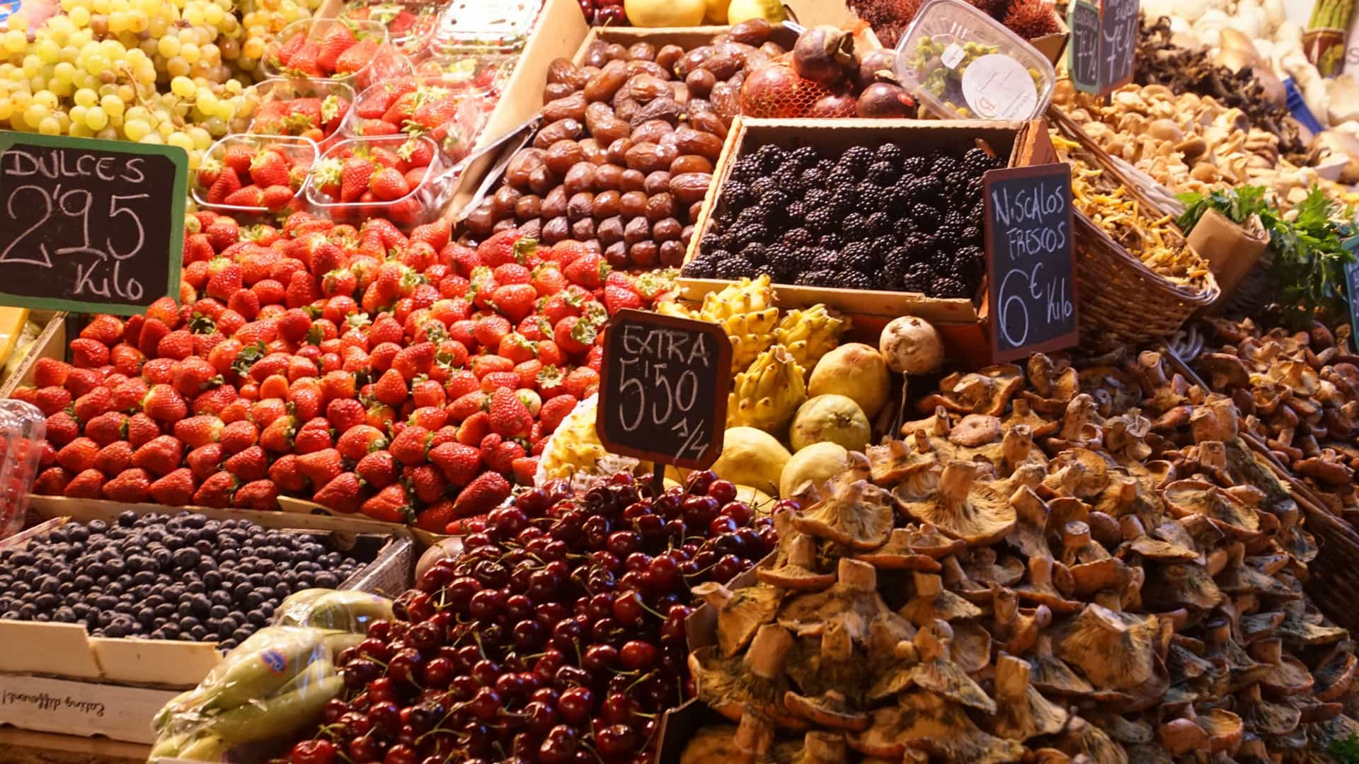 Vibrant stall of fresh produce inside the Mercado Central de Atarazanas (Shipyard Market) in Malaga, Spain, featuring colorful, artfully stacked displays of local and seasonal fruits and vegetables under the market's historic iron-and-glass structure.