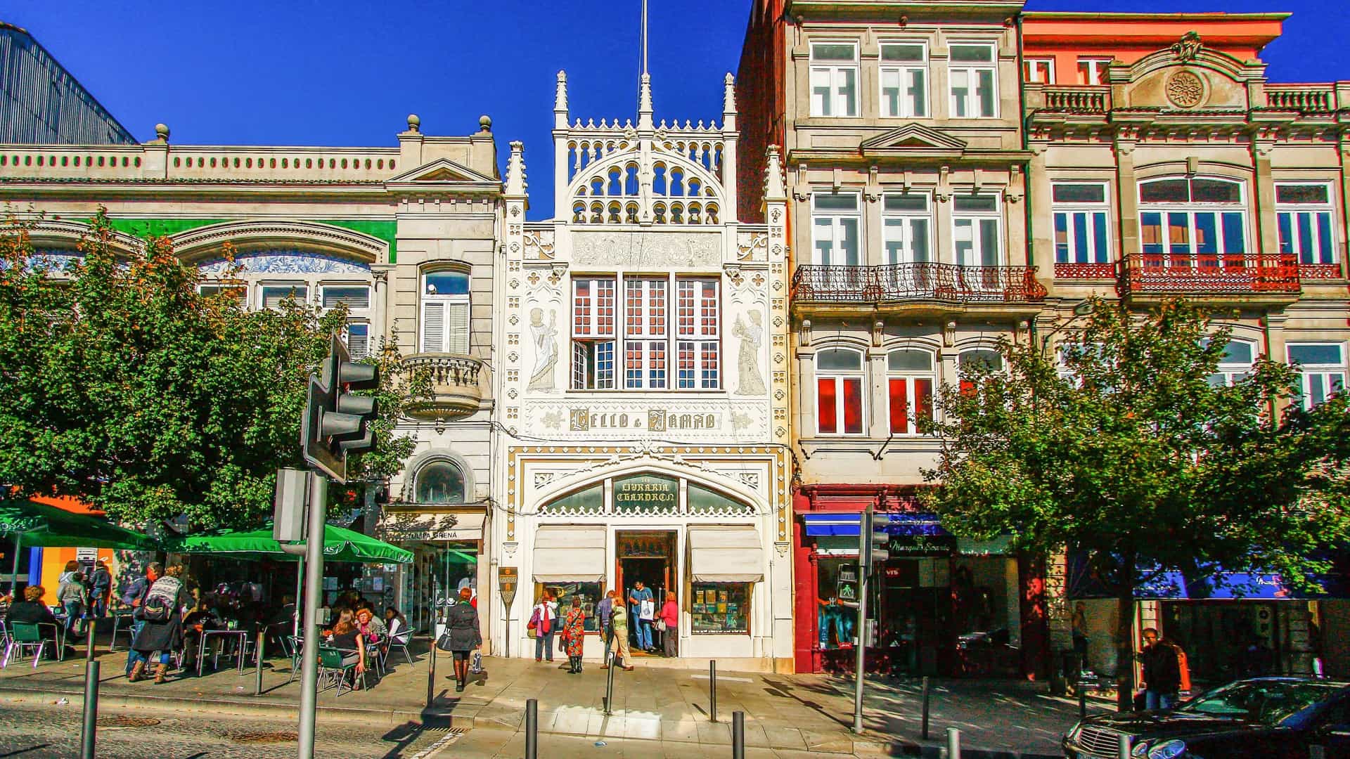 Livraria Lello bookstore interior in Porto, Portugal. Detailed view of the iconic, elaborate Neo Gothic red staircase, flanked by towering wooden bookshelves, beneath a large stained glass ceiling.