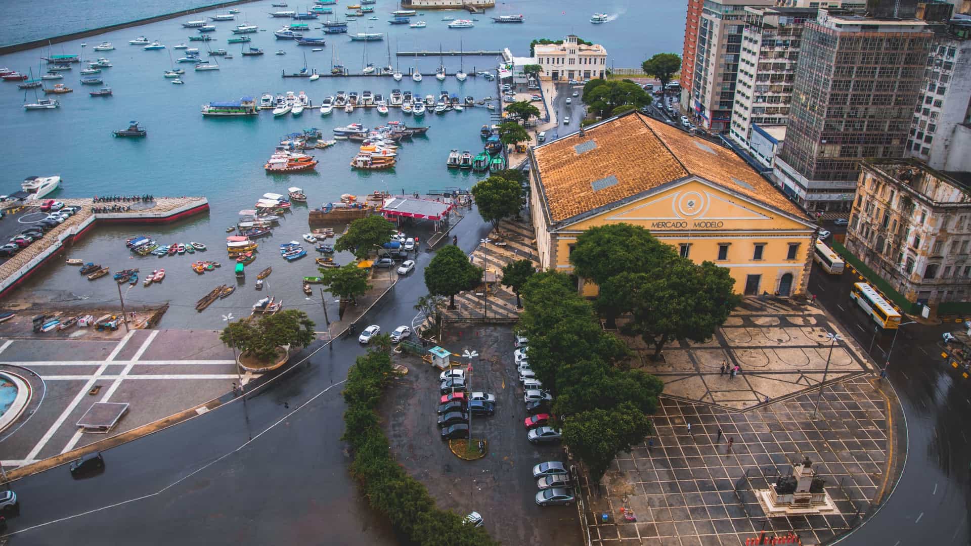 An exterior view of the Mercado Modelo (Model Market) in Salvador, Bahia, Brazil. The Neoclassical-style, two-story yellow building, which was once the city's customs house, sits prominently along the marine waterfront, serving as a famous market for Bahian handicrafts and a major tourist attraction.