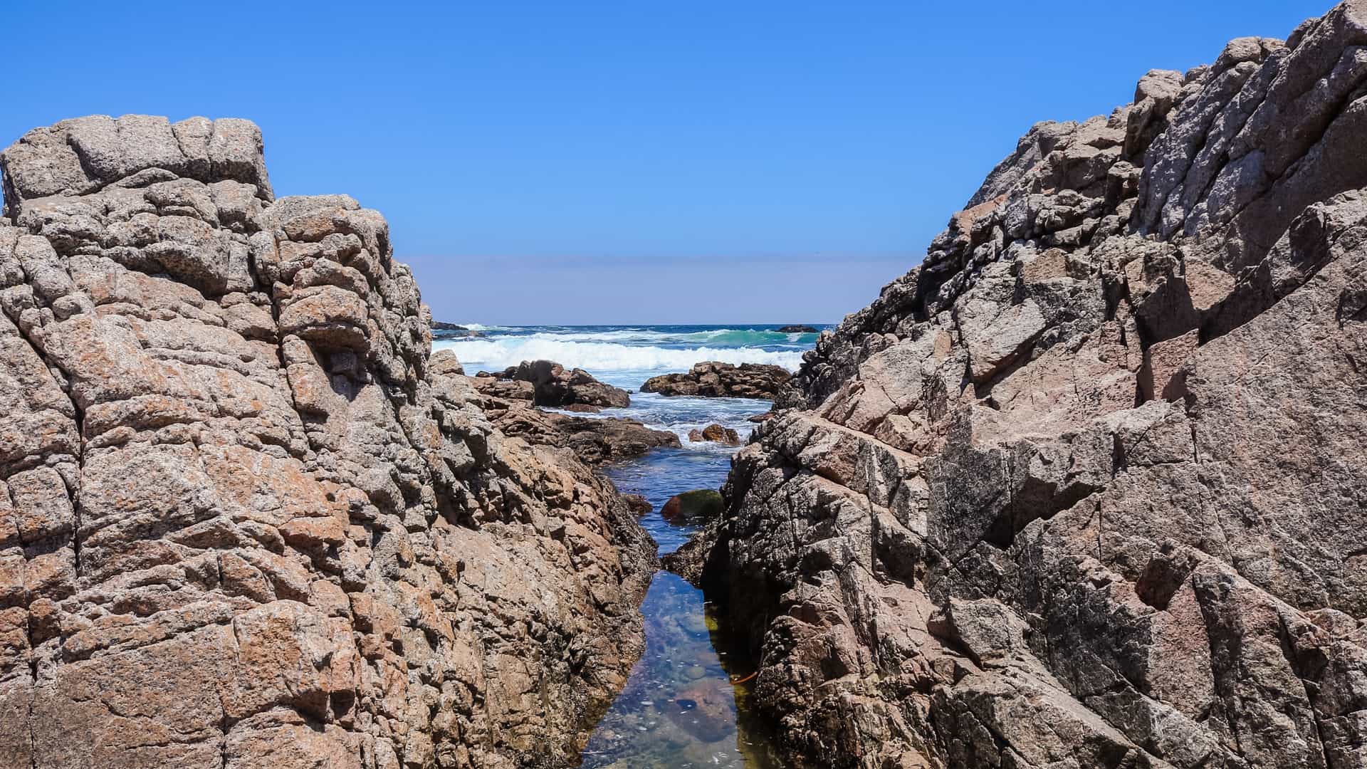  A scenic view of dramatic coastal cliffs and the Pacific Ocean in Algarrobo, Chile, with waves crashing against the rocky shoreline.