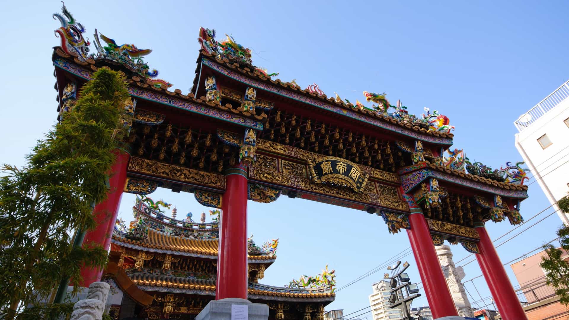  A vibrant street scene from Yokohama Chinatown (Chūkagai) in Japan, featuring one of its ornate, colorful traditional gates (like the Zenrinmon or Chouyomon) and crowded streets lined with buildings adorned with Chinese architecture, lanterns, and signs, typically bustling with visitors.