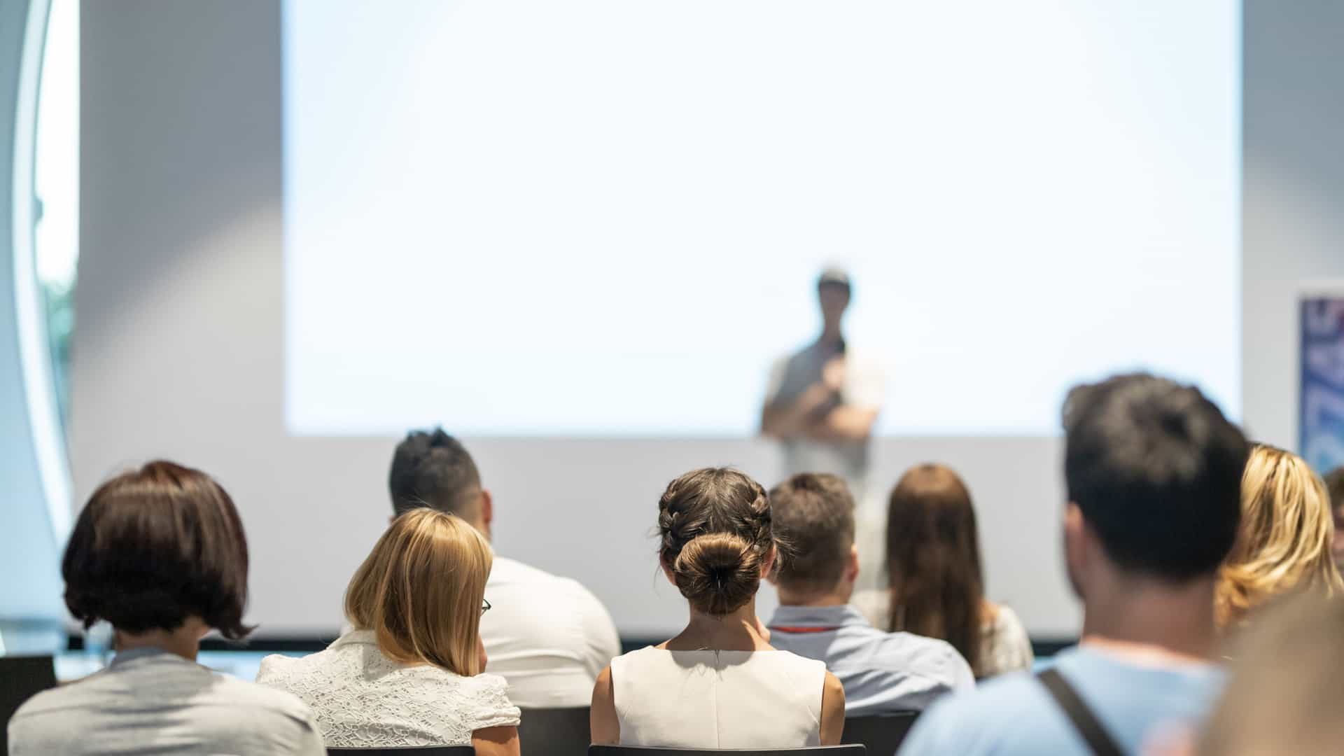 A group of people sitting together, listening attentively to a speaker in front of them on a cruise.