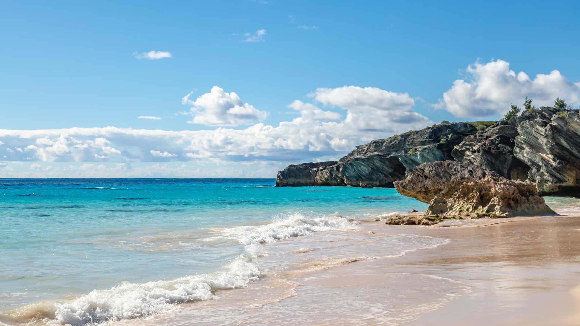 Explora journey view of a scenic pink sand beach and coastal rock formations with turquoise water in Bermuda.