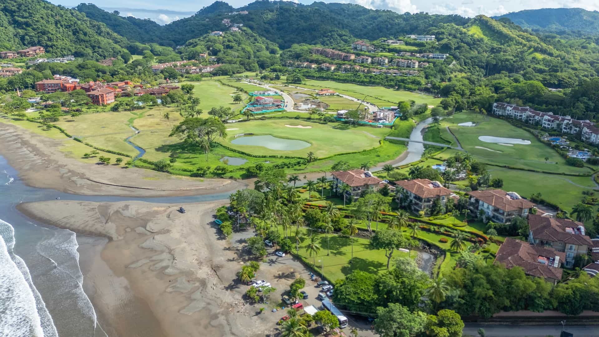 Explora journey aerial view of a coastal beach resort, golf course, and lush green mountains in Costa Rica.