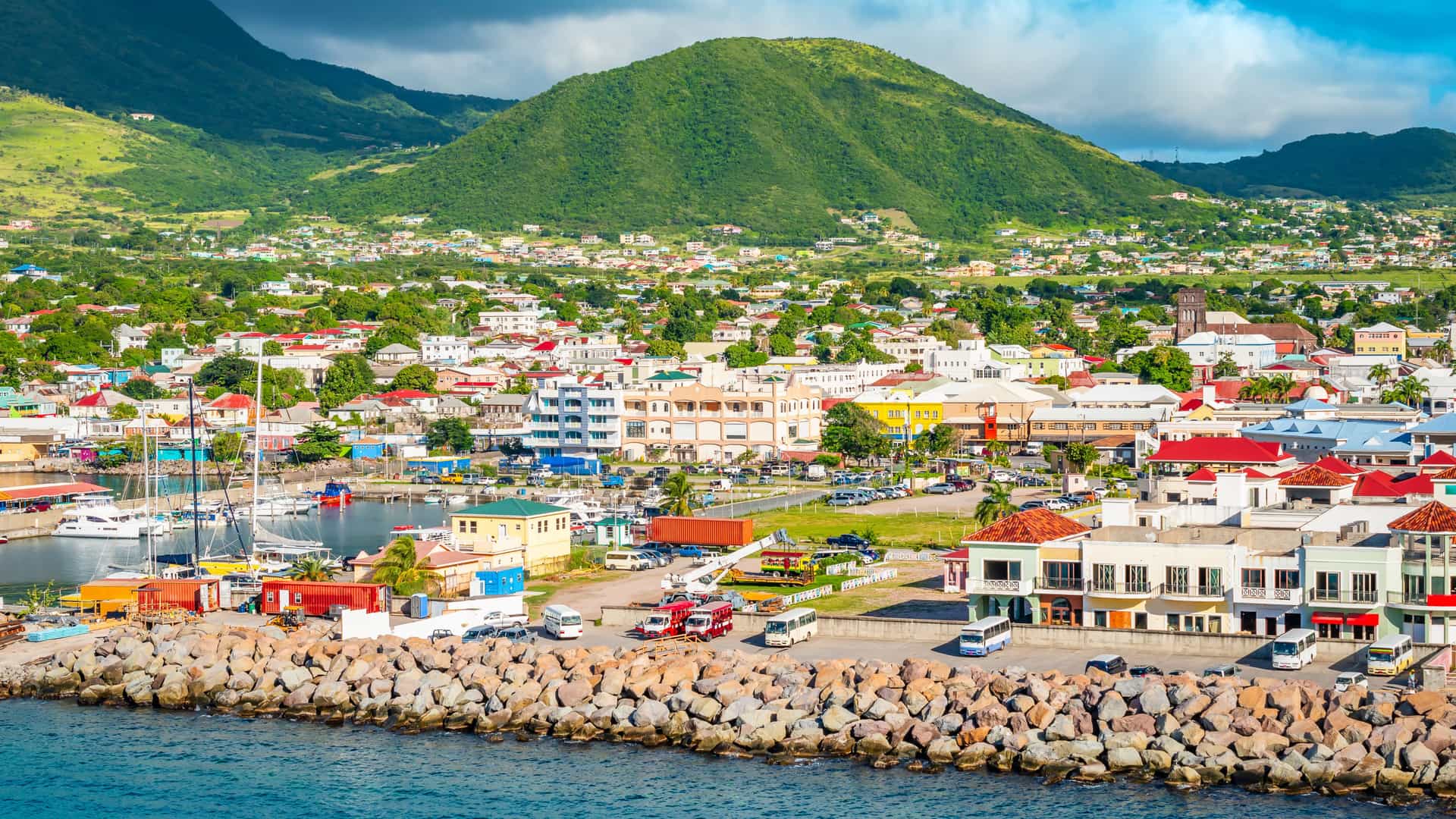 Explora journey view of a coastal port town and marina backed by lush green mountains in the Eastern Caribbean.